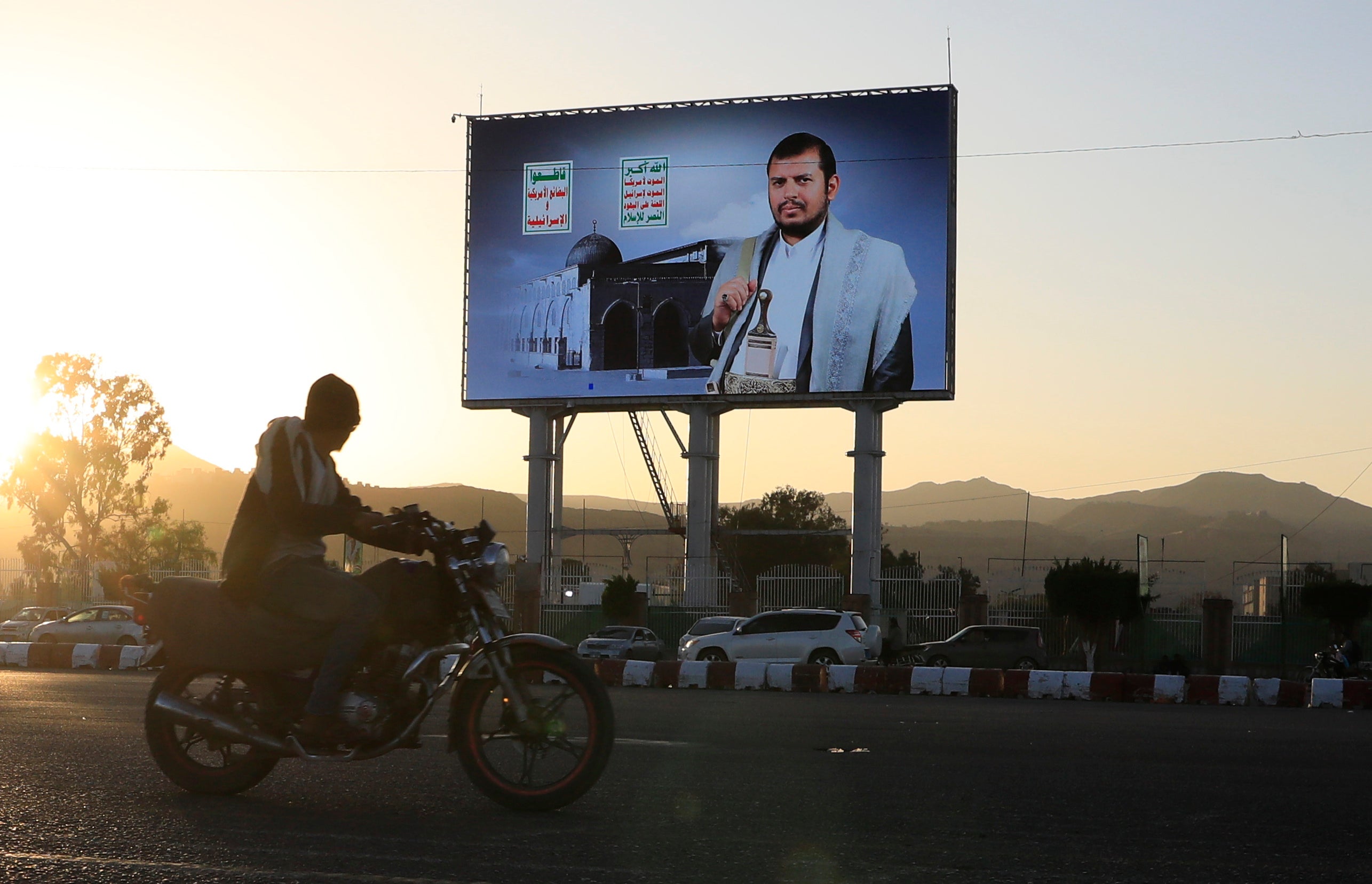 A motorcyclist drives past a large screen showing the top leader of the Houthis, Abdul-Malik al-Houthi, in Sana'a, Yemen