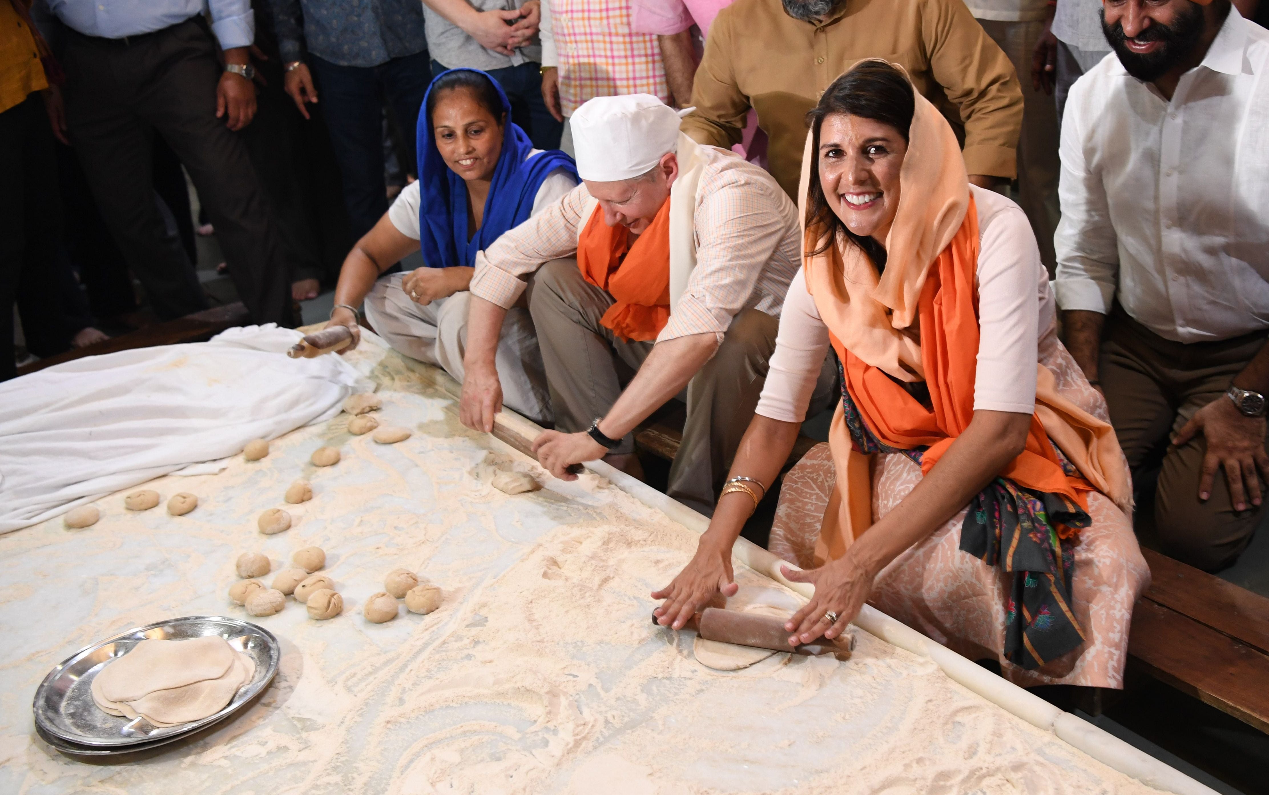 Haley makes bread in the kitchen of the Sis Ganj Gurudwara with US Ambassador to India Kenneth Juster, centre, in New Delhi, 2018