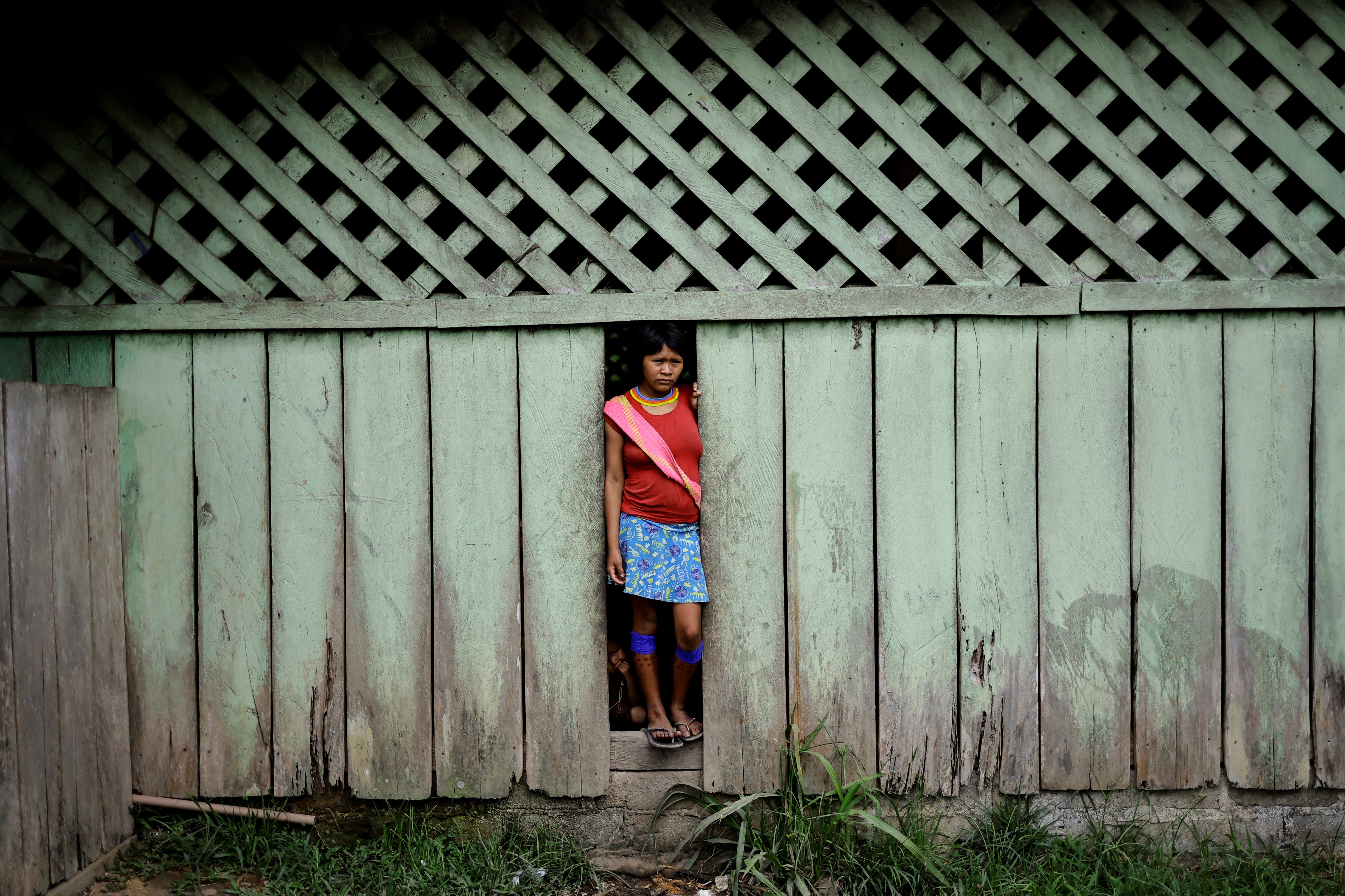 An Indigenous woman observes people outside of the Auaris Base Hub