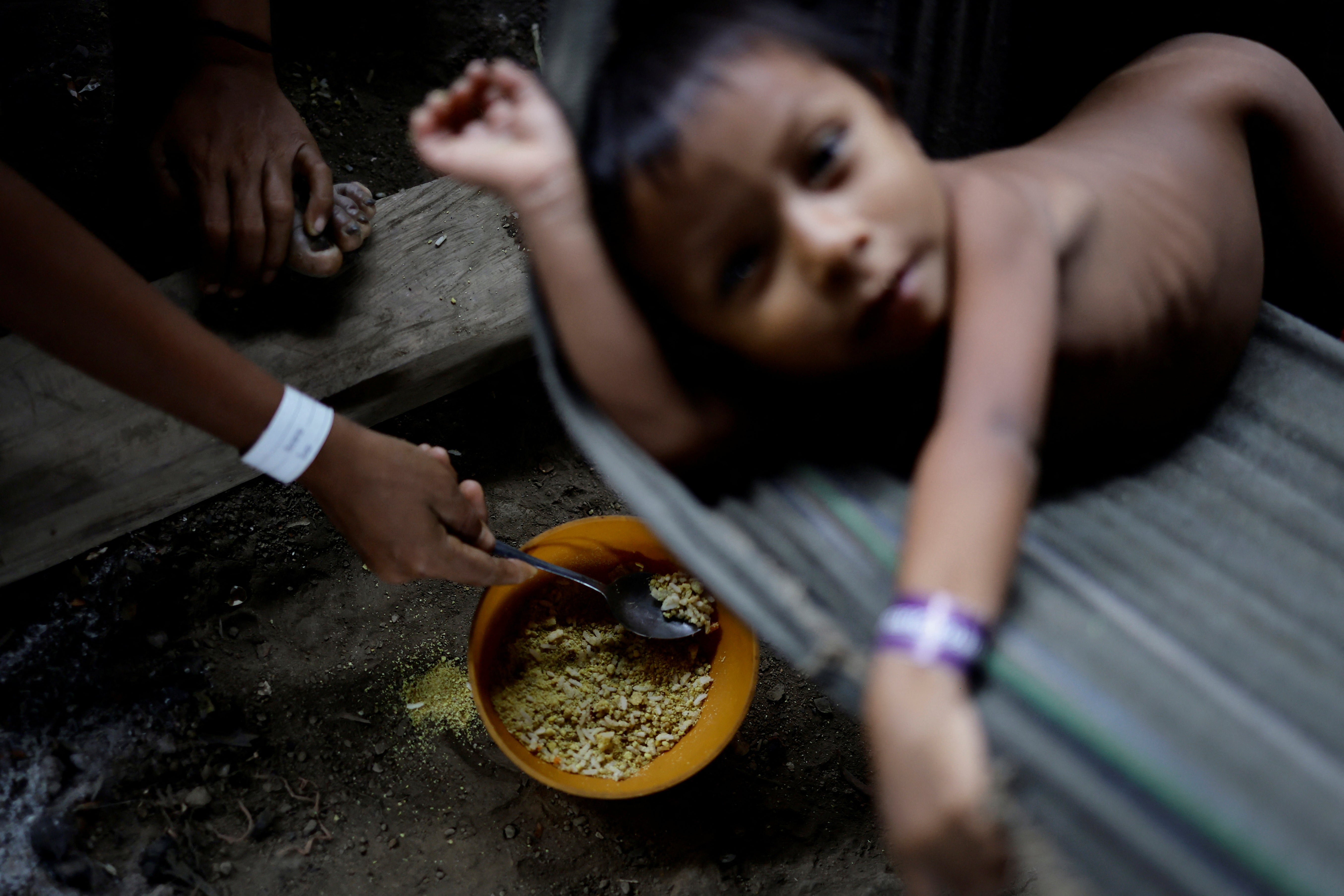 A Yanomami child is fed a mix of rice and farofa by his mother while receiving healthcare in the accommodation used to shelter the sick, at the healthcare unit of the Auaris Base Hub, in Yanomami Indigenous land