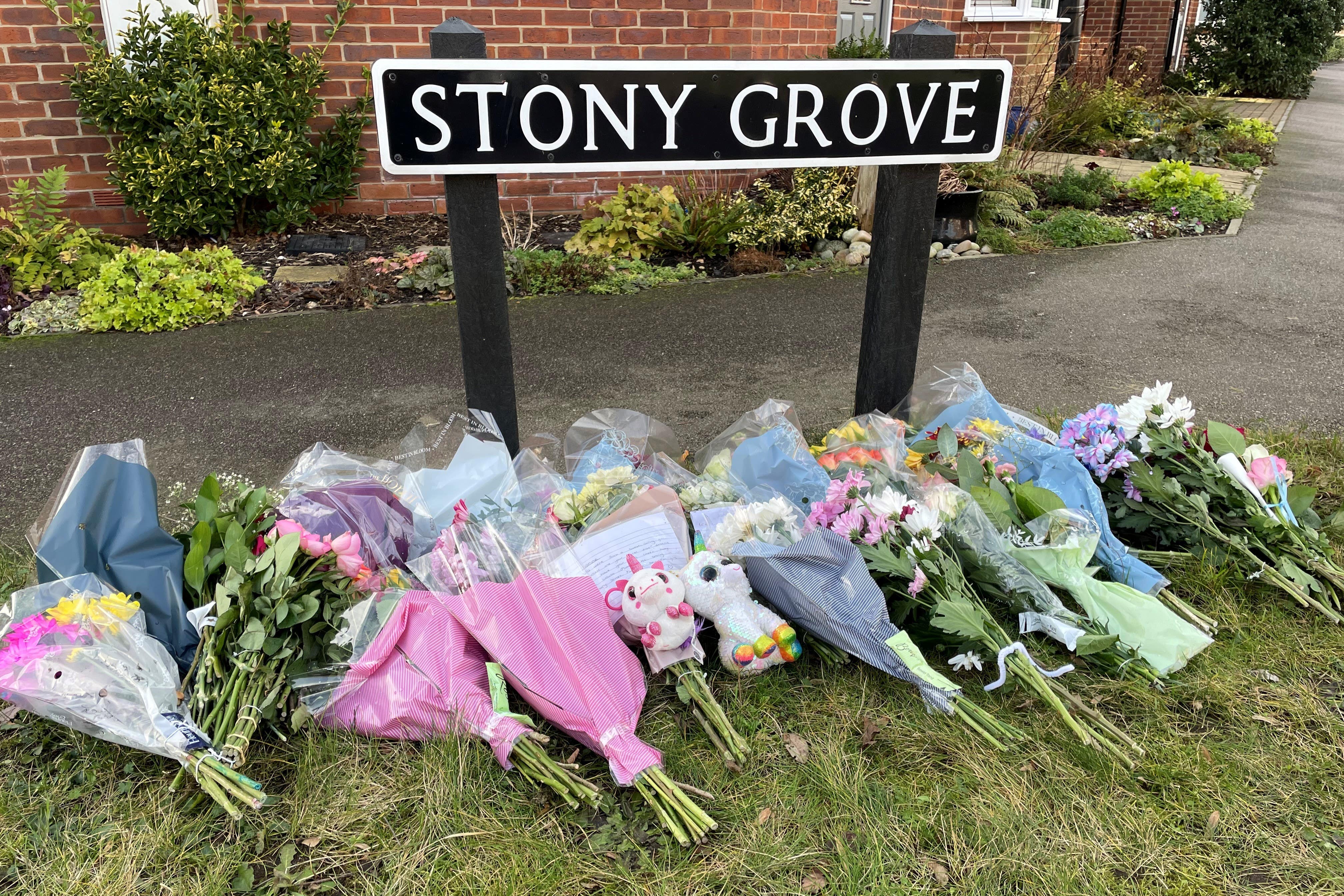 Flowers laid near the house where four people were found dead on Friday (PA)