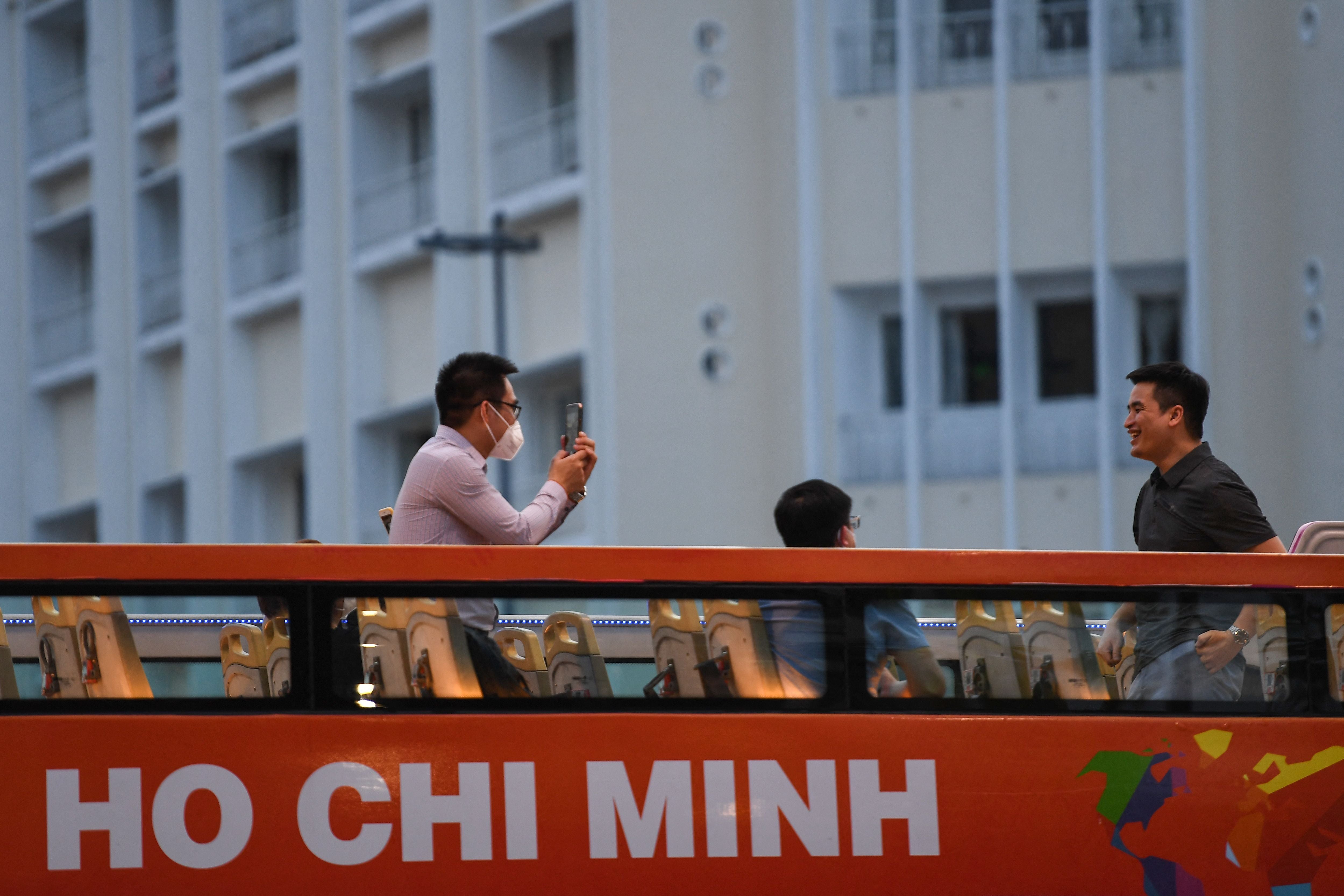 Representative: A tourist takes a photo with his mobile phone as people tour Ho Chi Minh City in a sightseeing bus on 1 December 2021