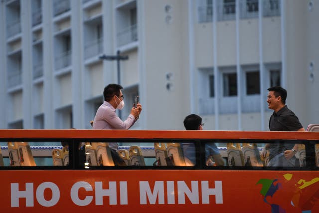 <p>Representative: A tourist takes a photo with his mobile phone as people tour Ho Chi Minh City in a sightseeing bus on 1 December 2021</p>