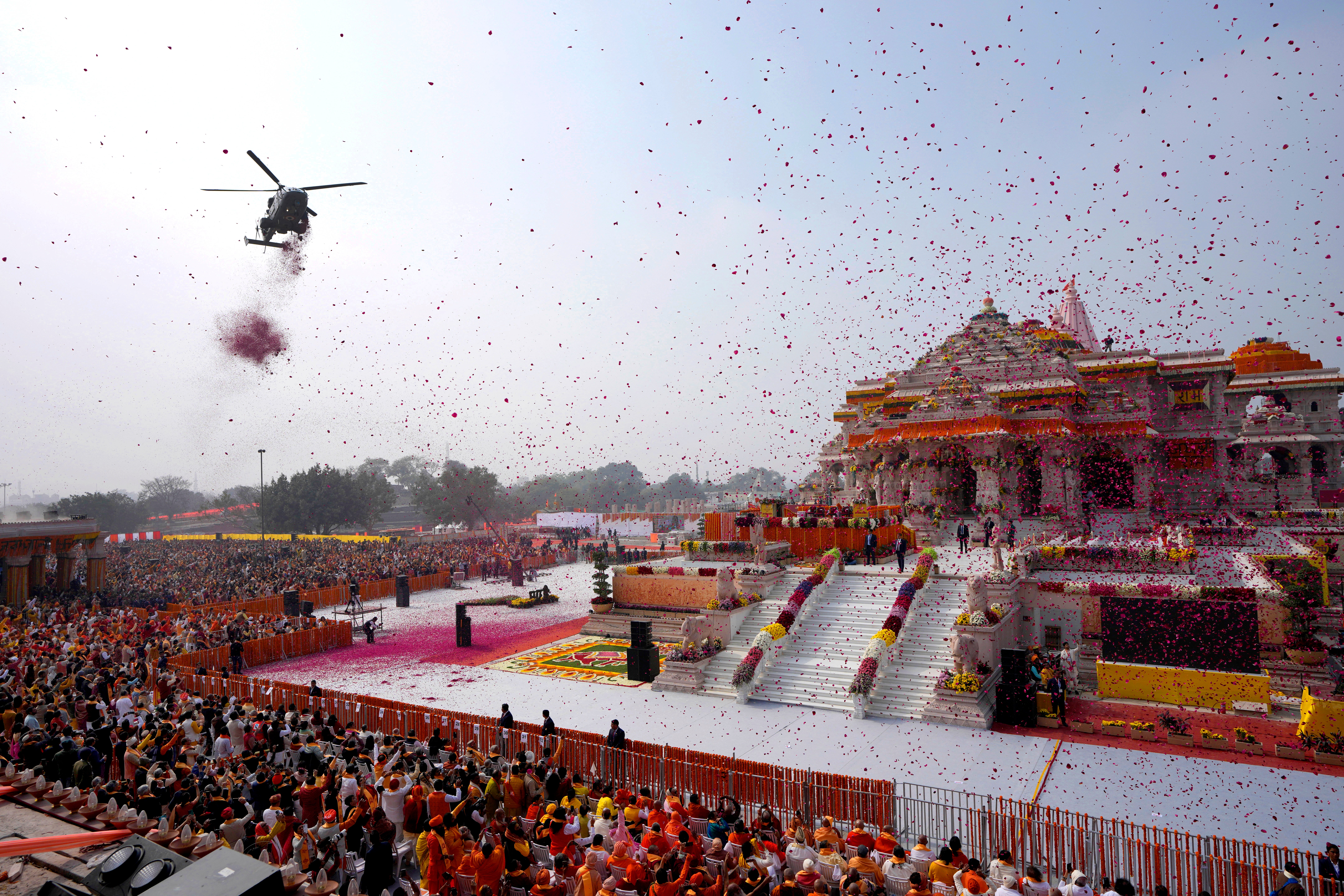 An Indian Air Force helicopter showers flower petals during the opening of Ram temple
