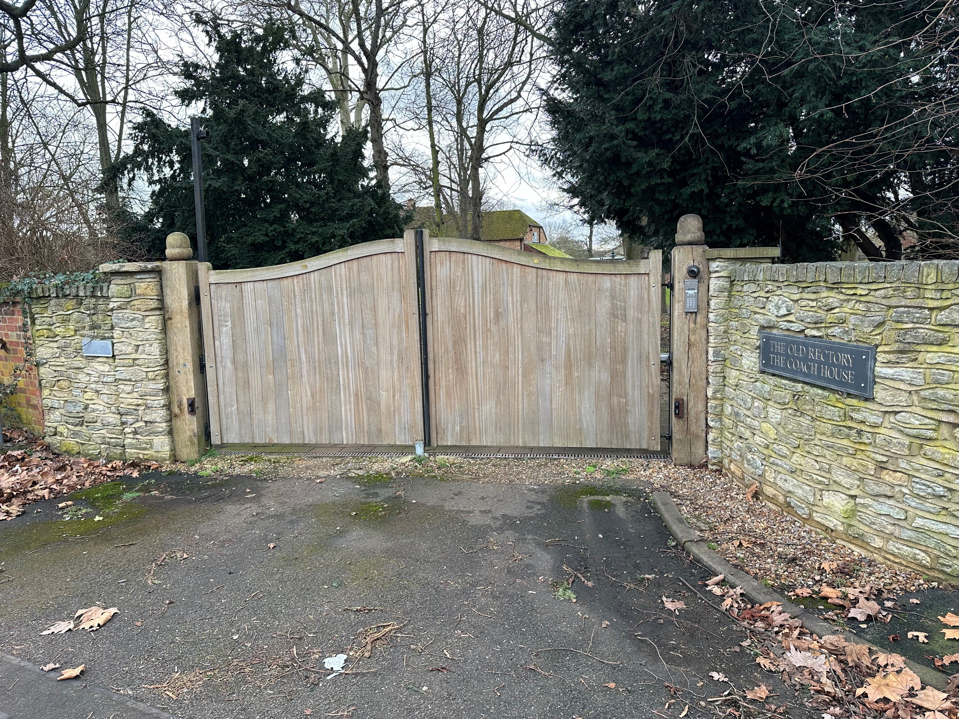 The gated entrance to The Old Rectory. Fencing and trees surround the boundary to the house and garden