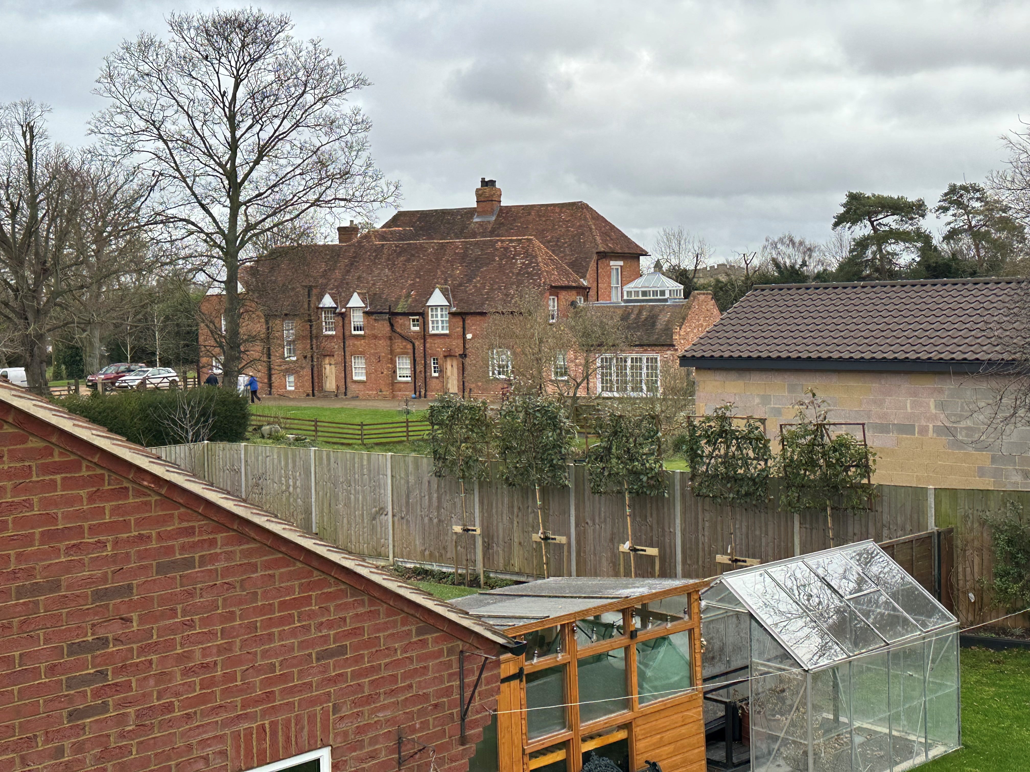The view of the building (on the right) behind garden fences facing The Old Rectory