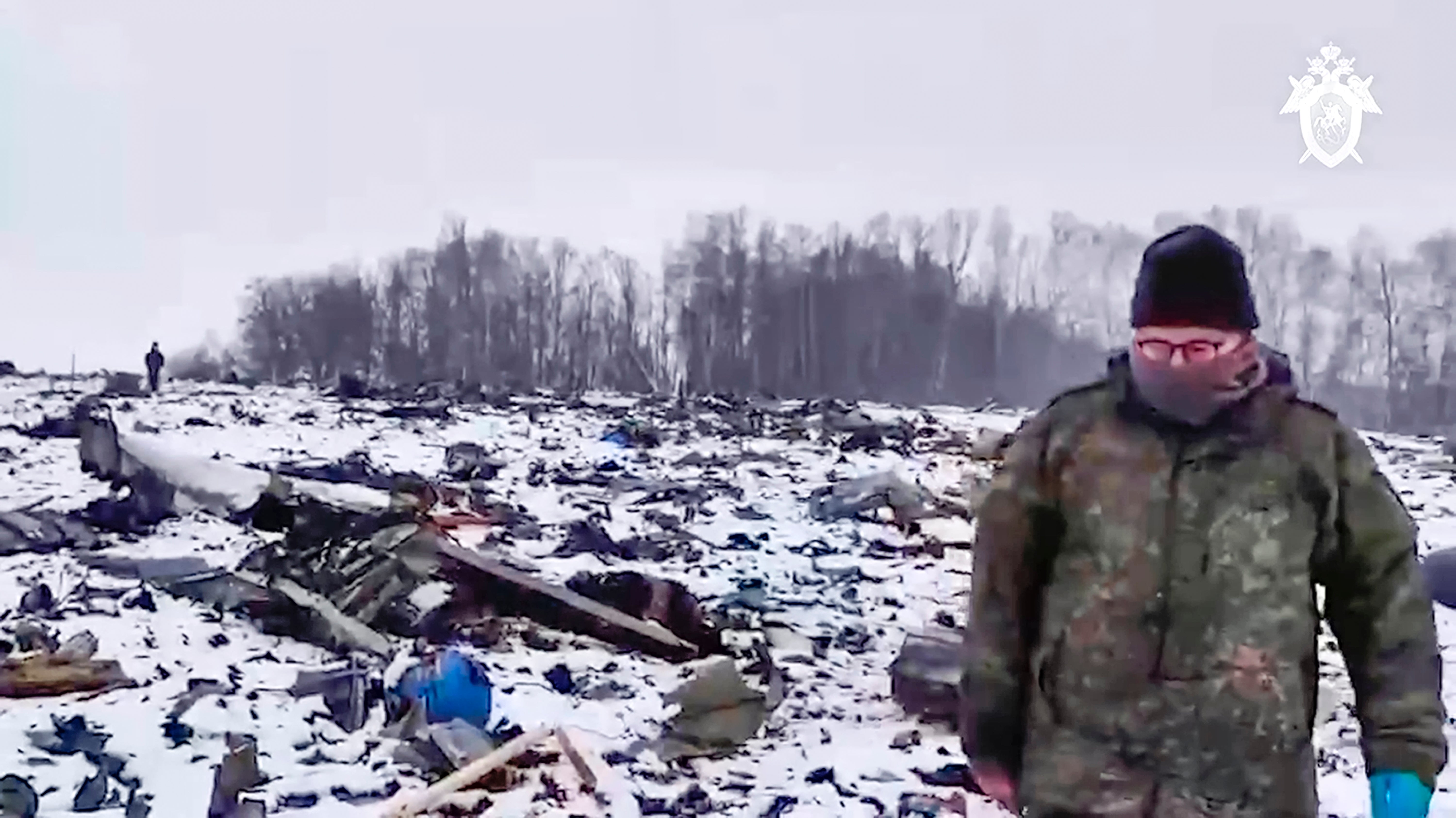 Russian Investigative Committee employee walks in a place with wreckage of the Russian military Il-76 plane crashed area near Yablonovo, Belgorod region of Russia