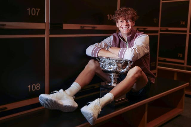 Jannik Sinner poses with the trophy in the locker room (Fiona Hamilton/Tennis Australia via AP)