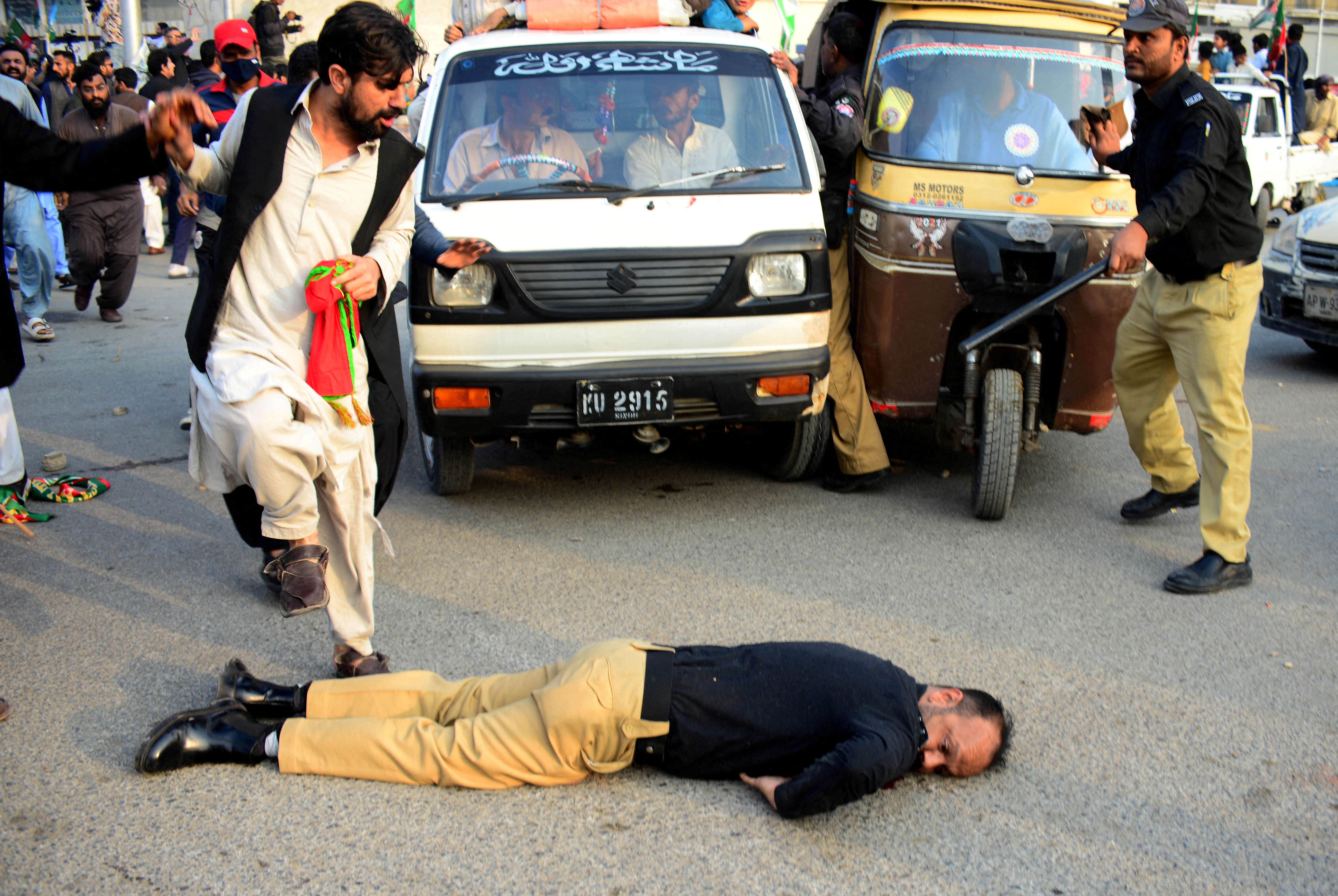 An injured police officer lies on the road during a clash with supporters of former PM Khan's party, the Pakistan Tehreek-e-Insaf, in Karachi