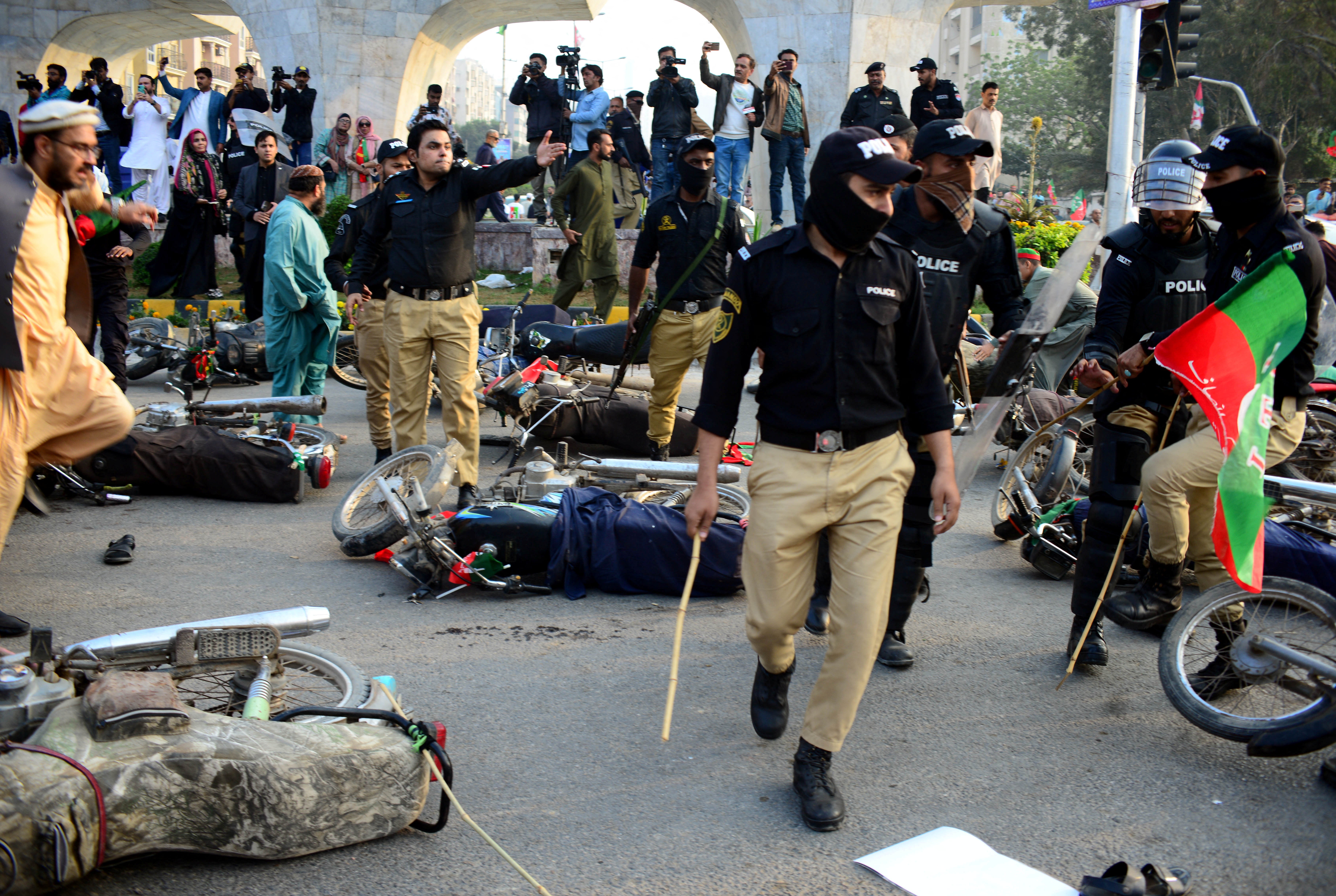 Police officers gesture next to fallen motorbikes of supporters of former prime minister Imran Khan's party,