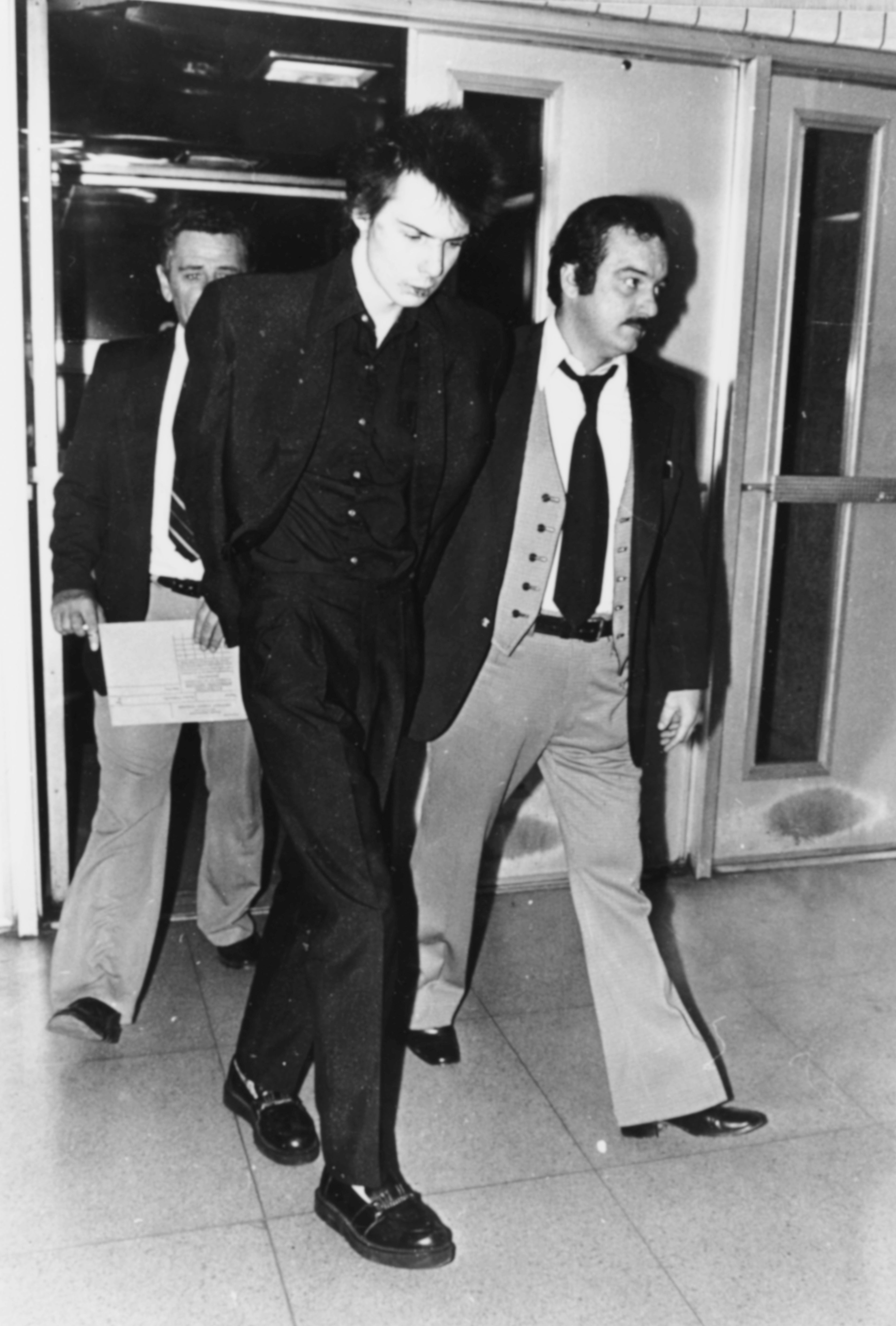 Sid Vicious is led away in police custody on a charge of murder after his girlfriend Nancy Spungen was found stabbed to death in a hotel room, New York City, November 1978