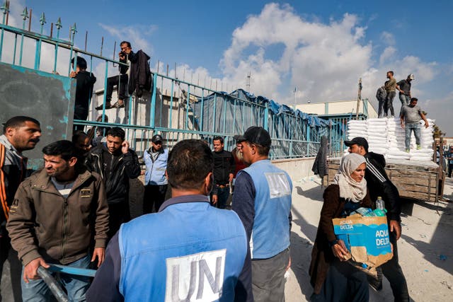 <p>Workers of the United Nations Relief and Works Agency for Palestine Refugees (UNRWA) hand out flour rations and other supplies to people at an UNRWA warehouse in Rafah in the southern Gaza Strip</p>