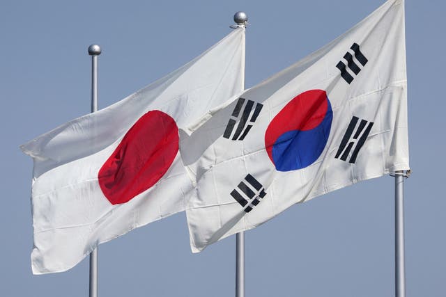 <p>The national flags of Japan (L) and South Korea (R) flutter in the wind on 16 March 2023</p>