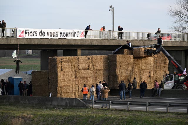 <p>A banner reading ‘Proud to feed you!’ is seen at a road blockade built by farmers on the A4 highway near Paris </p>