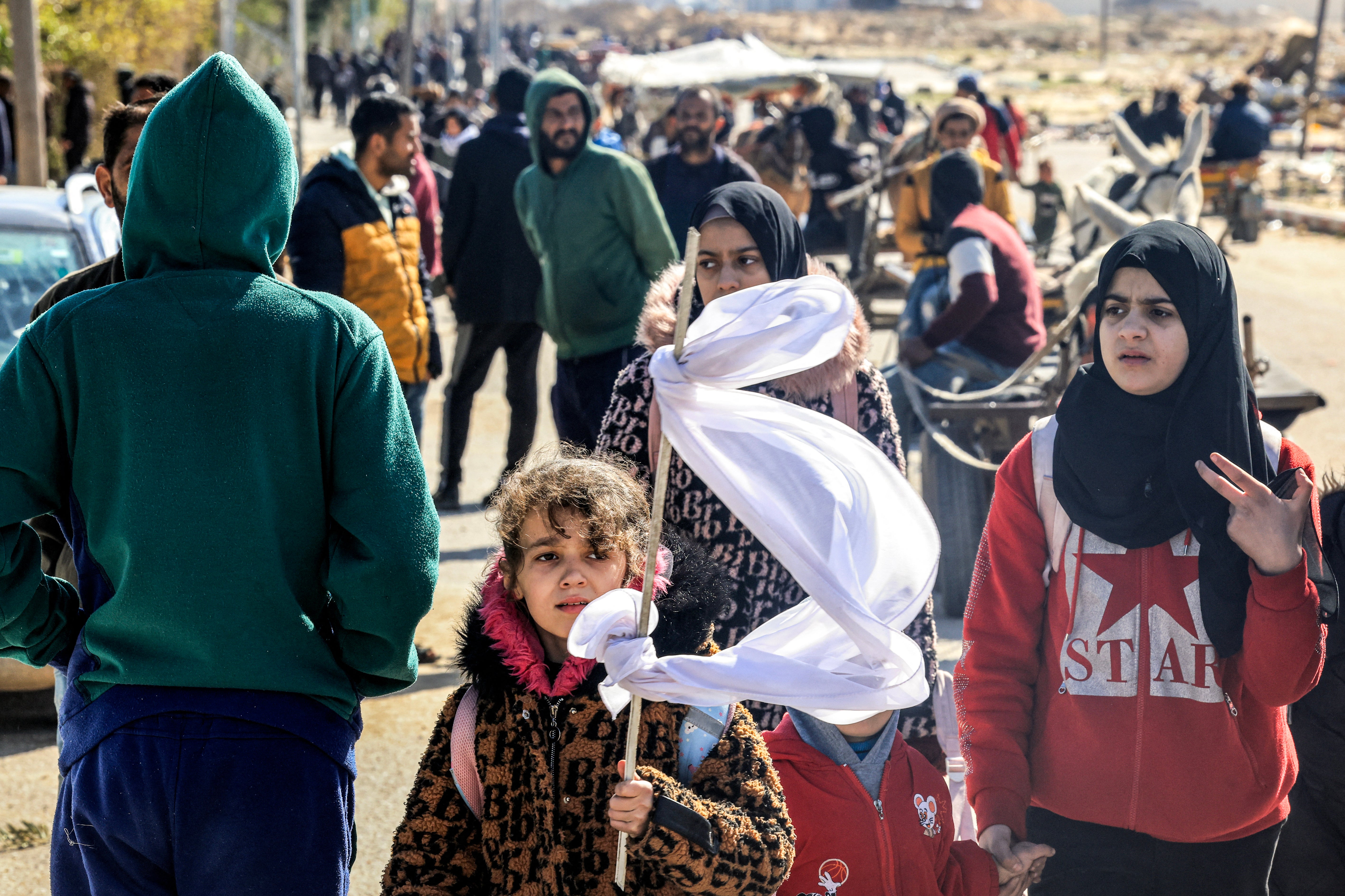 A girl holds a makeshift white flag as she walks with other displaced Palestinians fleeing from Khan Younis in the southern Gaza Strip