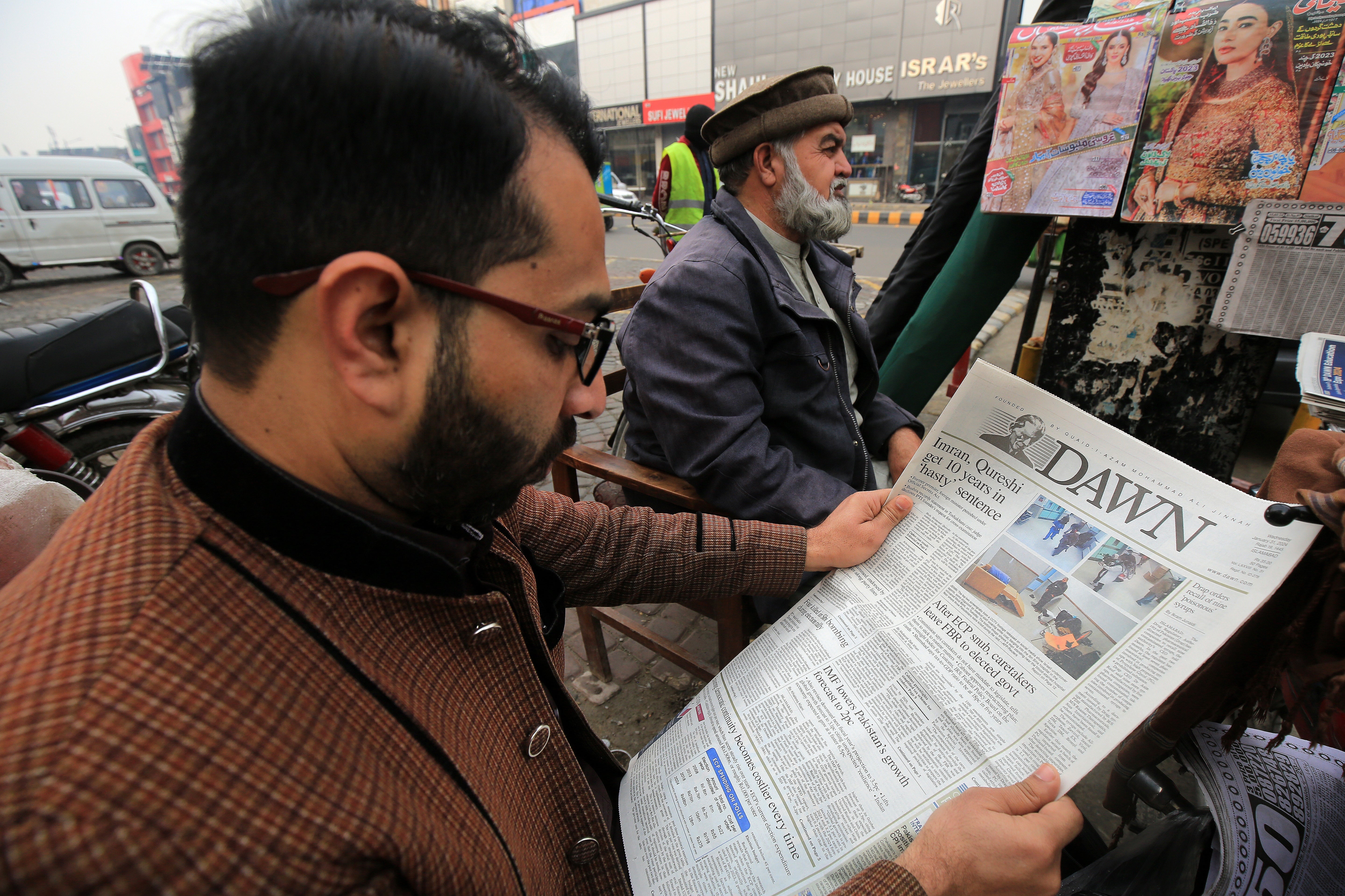 A man reads a newspaper reporting on the imprisonment sentence against former Prime Minister Imran Khan in Peshawar,