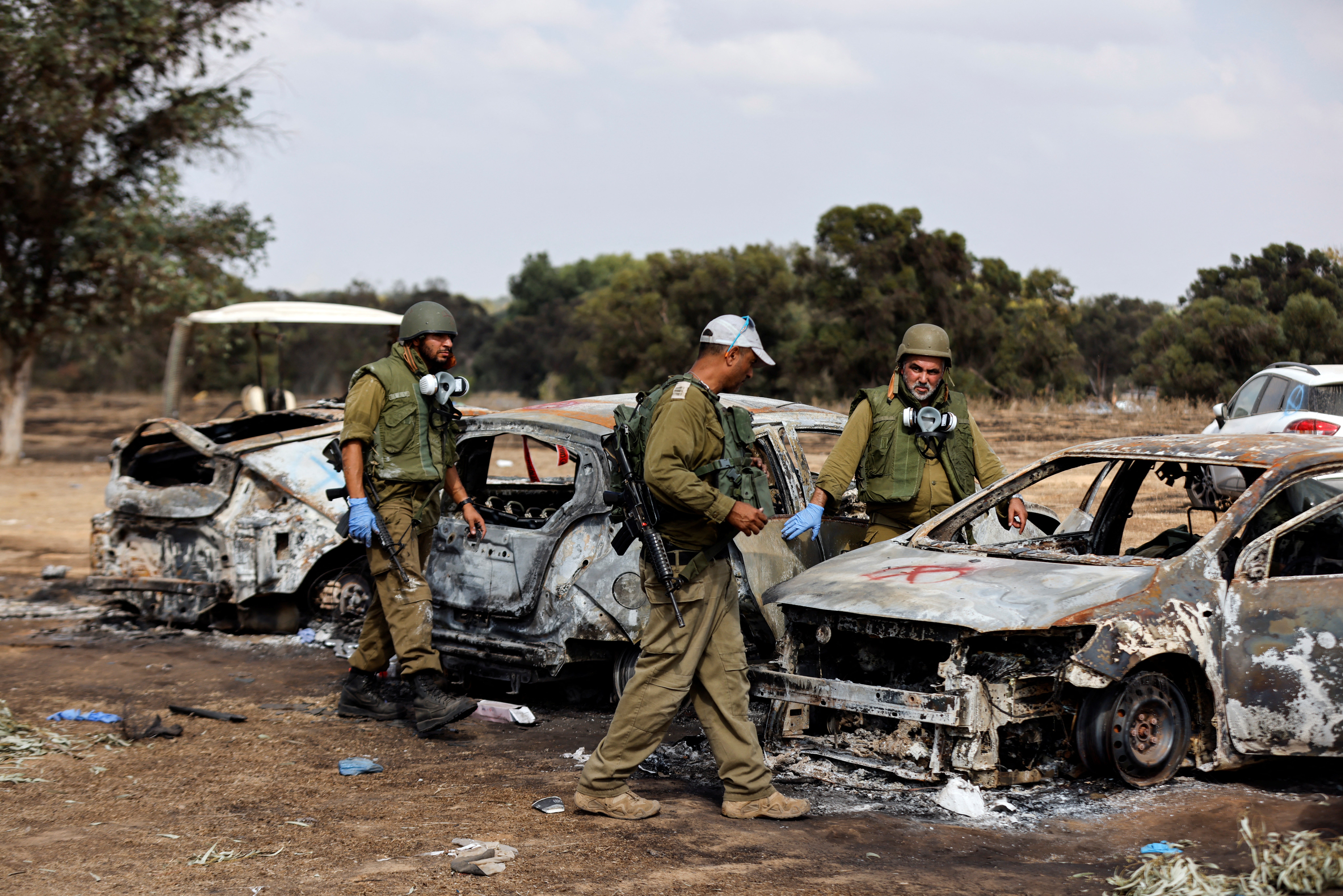 Israeli soldiers inspect the burnt cars of festival-goers at the site of an attack on the Nova Festival by Hamas gunmen from Gaza
