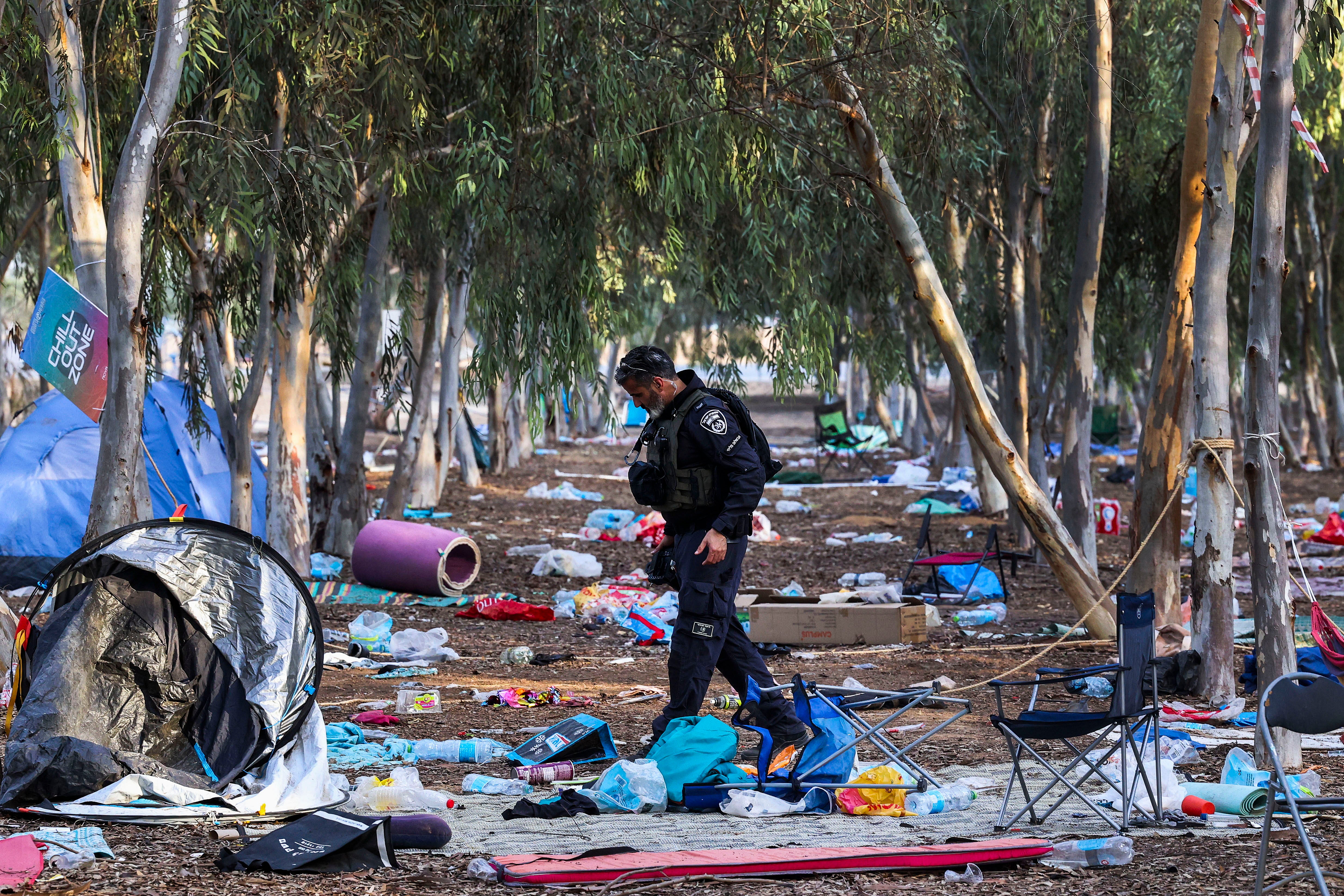 An Israeli officer walks on the ground of the Nova music festival in Re'im, Israel after the event was attacked by Hamas on 7 October