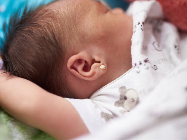 <p>Sleeping newborn baby with pierced ear</p>