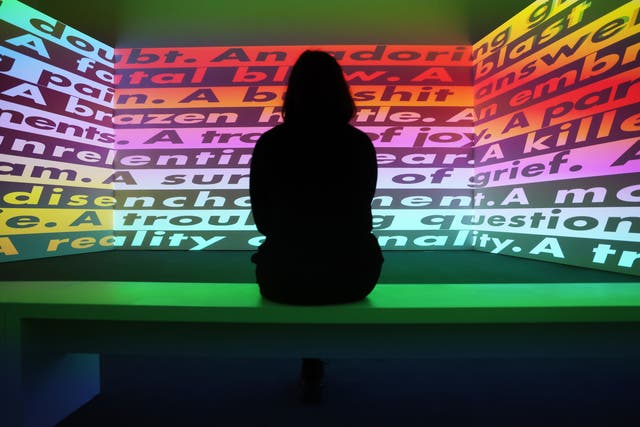 <p>A Serpentine Gallery worker looks at a video work by US artist Barbara Kruger</p>