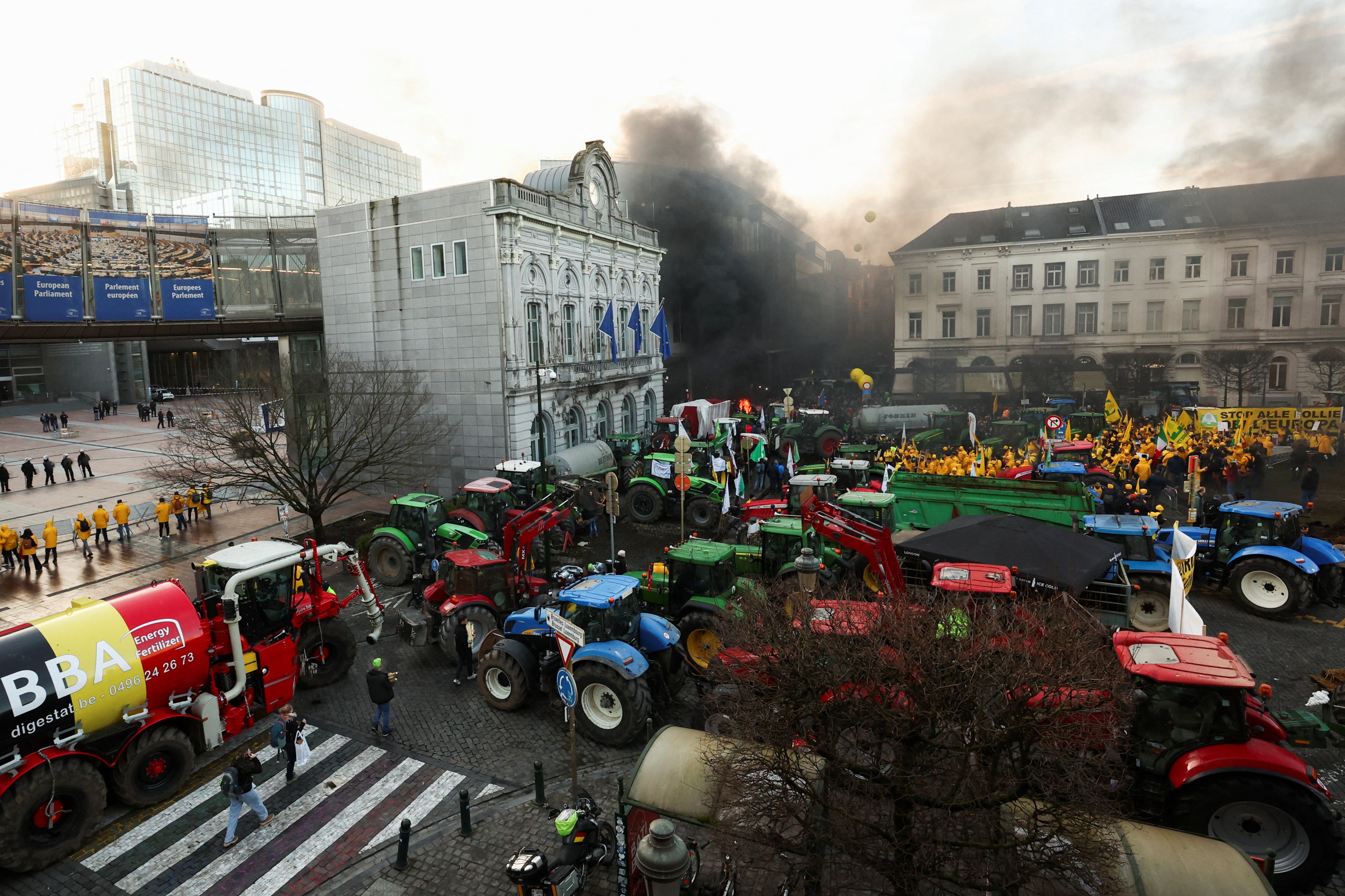 Smoke rises from a fire burning as Belgian farmers use their tractors to block roads