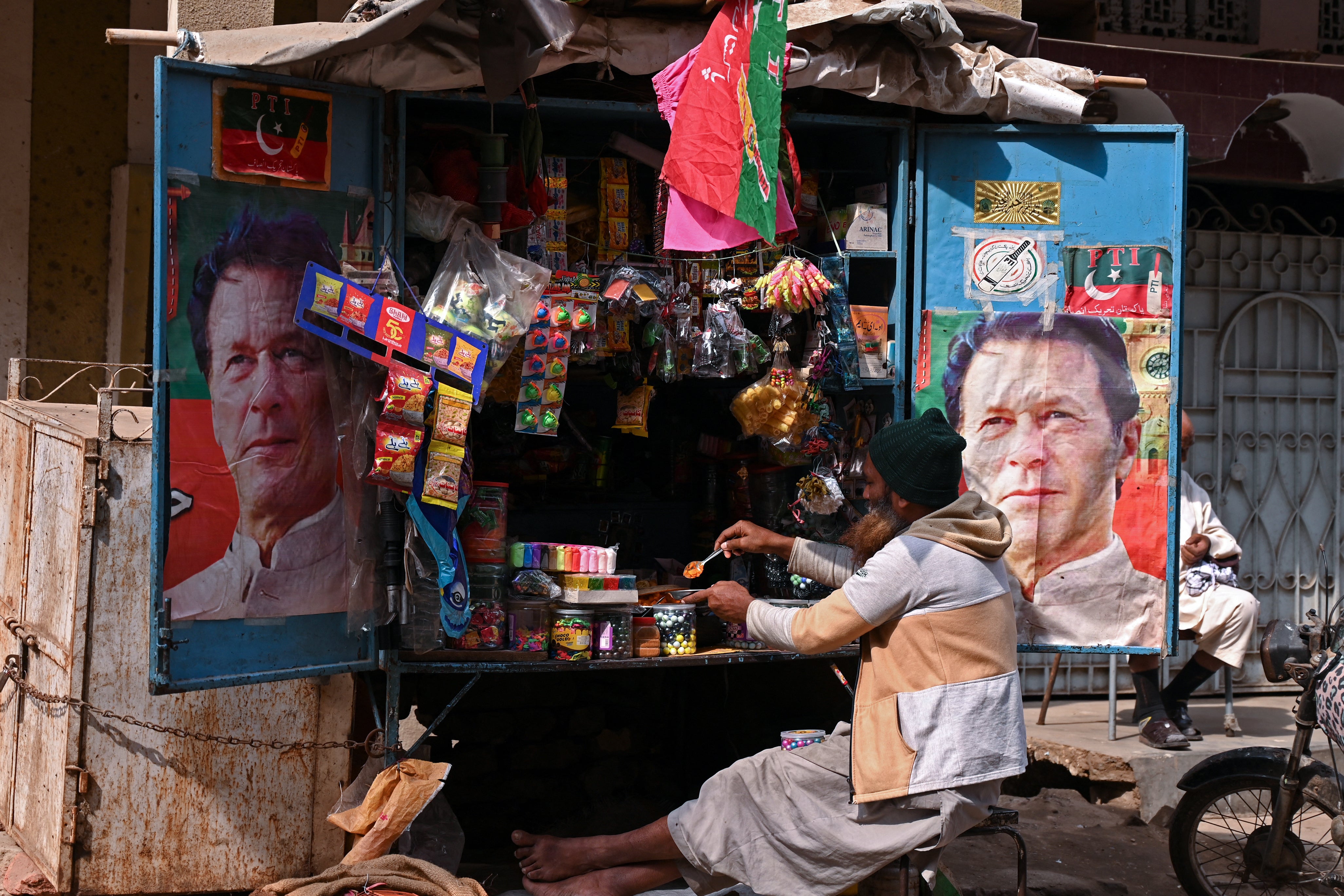 A vendor sits at his tuck shop displaying posters of Pakistan’s former prime minister and Pakistan Tehreek-e-Insaf (PTI) leader Imran Khan
