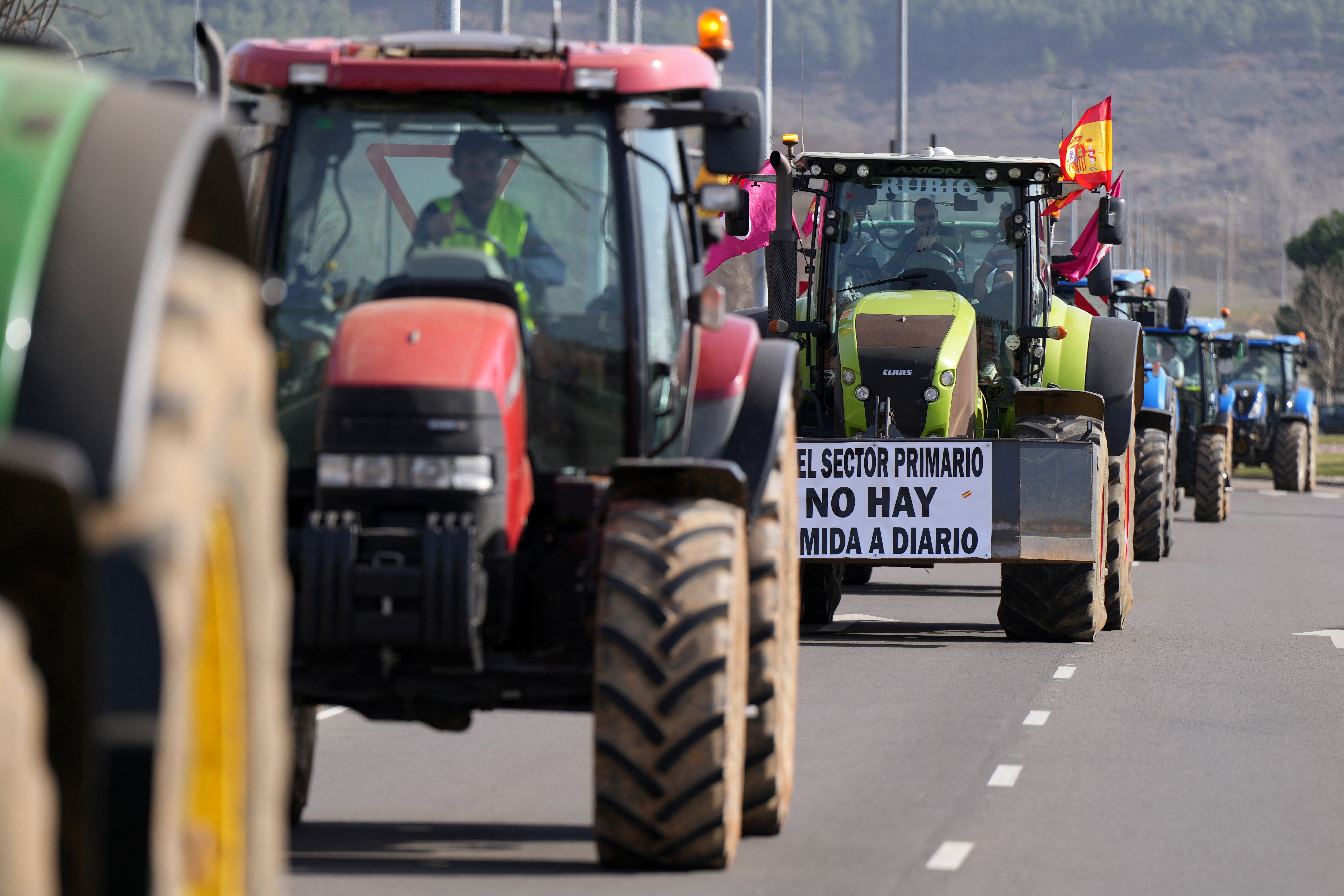 Spanish farmers drive their tractors along the road during a protest in demand of fair conditions