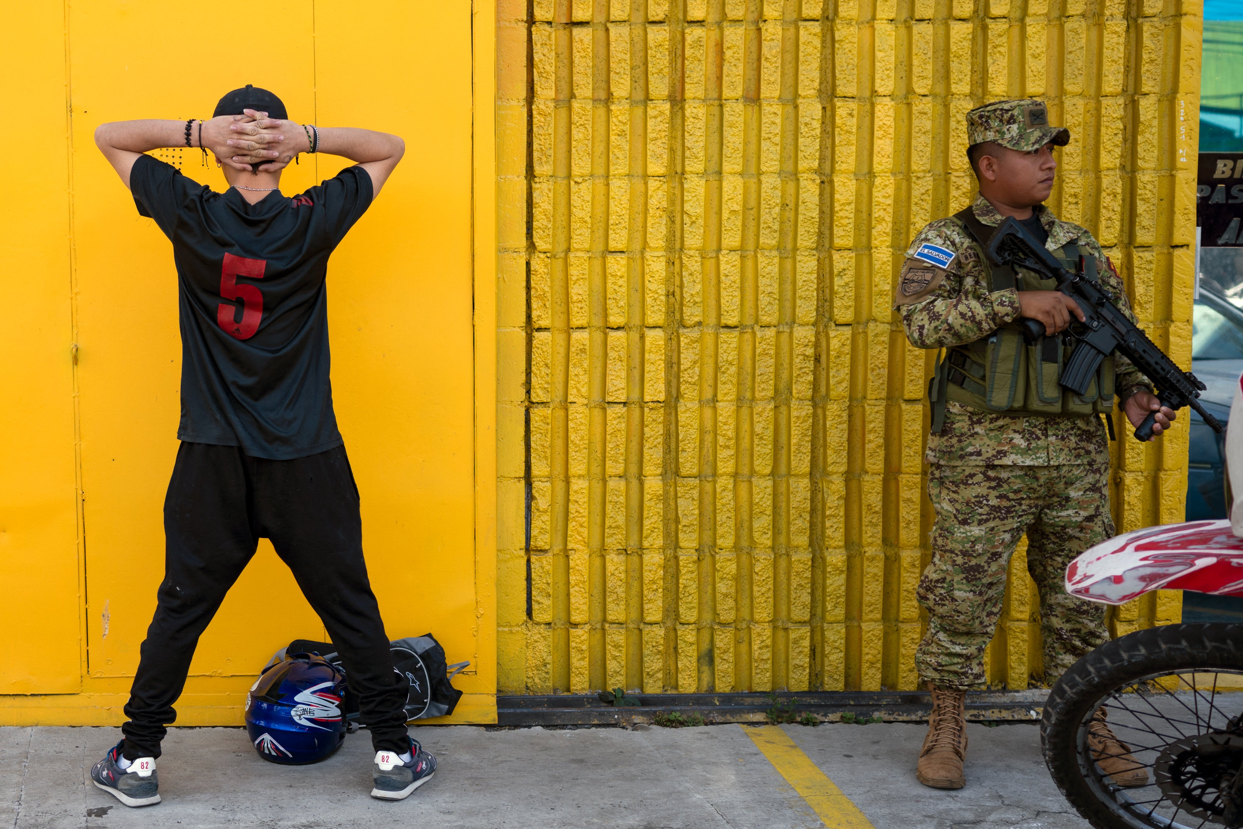 A soldier guards a detained youth in San Salvador ahead of Sunday’s presidential election