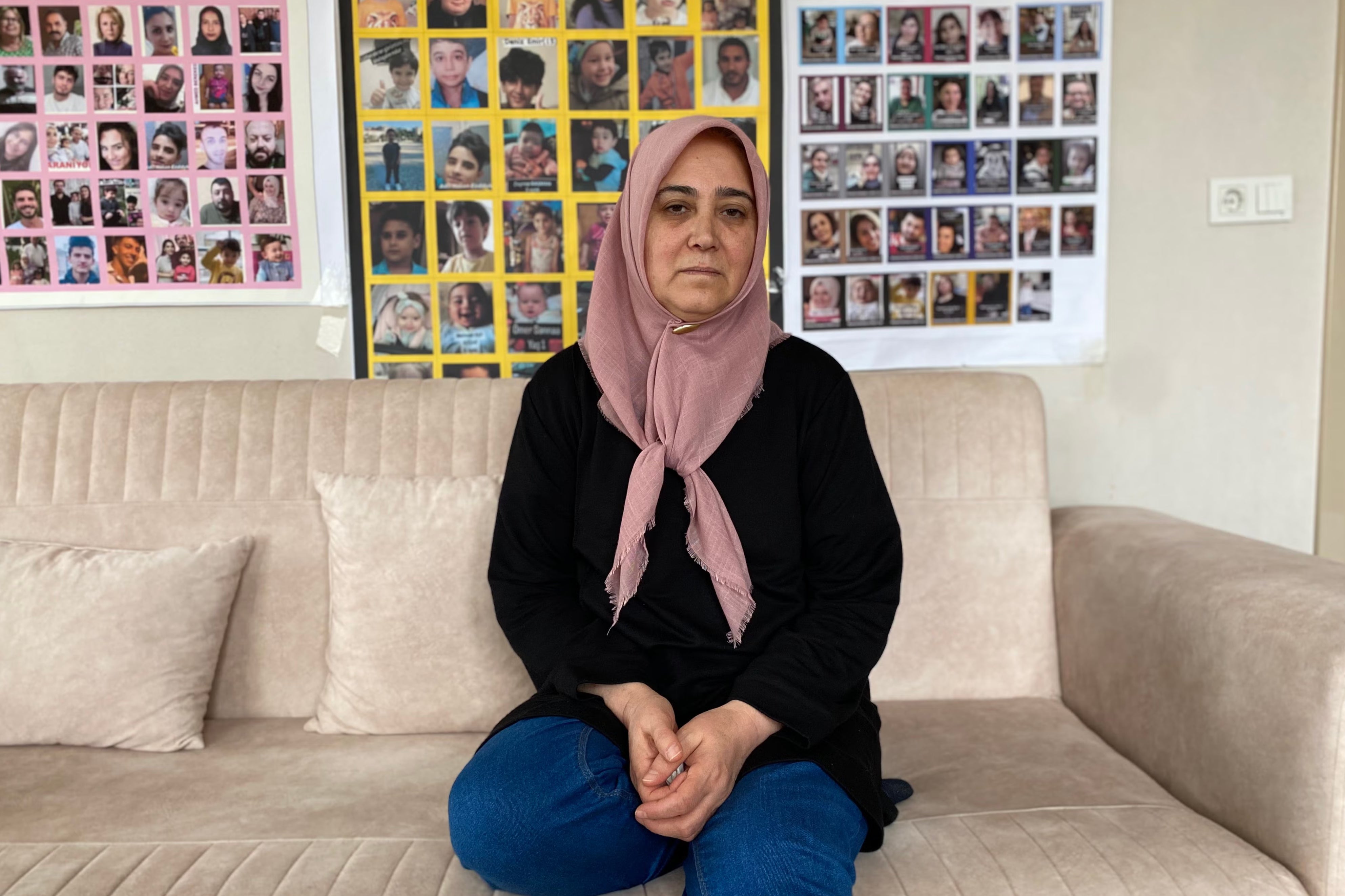 Suna Ozturk sits in front of a poster of people missing since the earthquakes in Turkey, while at home in Aksaray. Her daughter and two grandsons went missing in the disaster