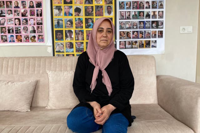<p>Suna Ozturk sits in front of a poster of people missing since the earthquakes in Turkey, while at home in Aksaray. Her daughter and two grandsons went missing in the disaster</p>