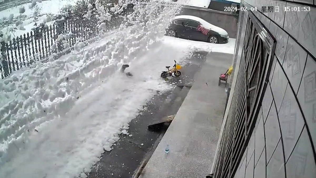 Moment woman shovelling show buried under avalanche from roof