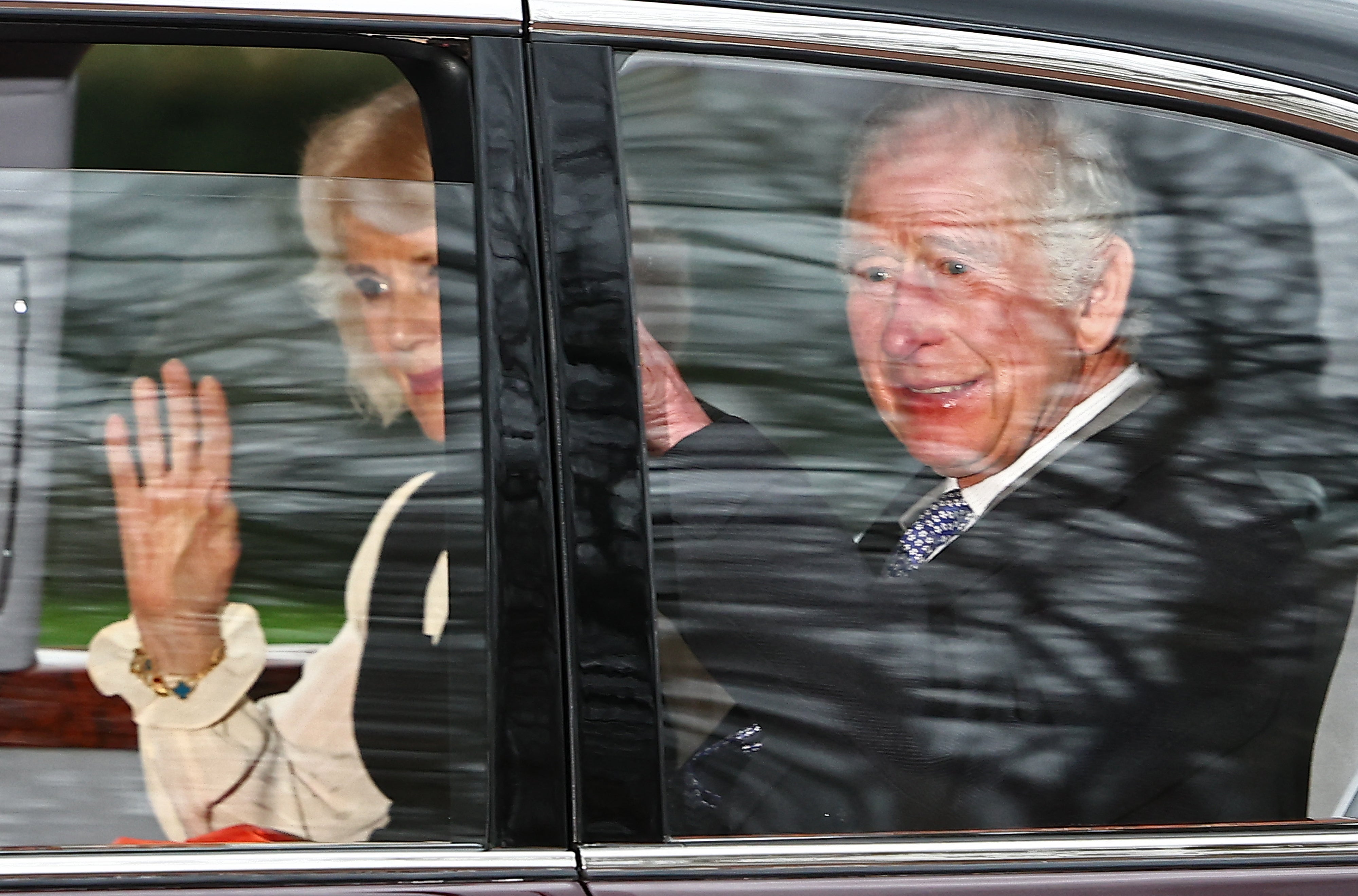 Britain's King Charles III and Britain's Queen Camilla wave as they leave by car from Clarence House in London on Tuesday