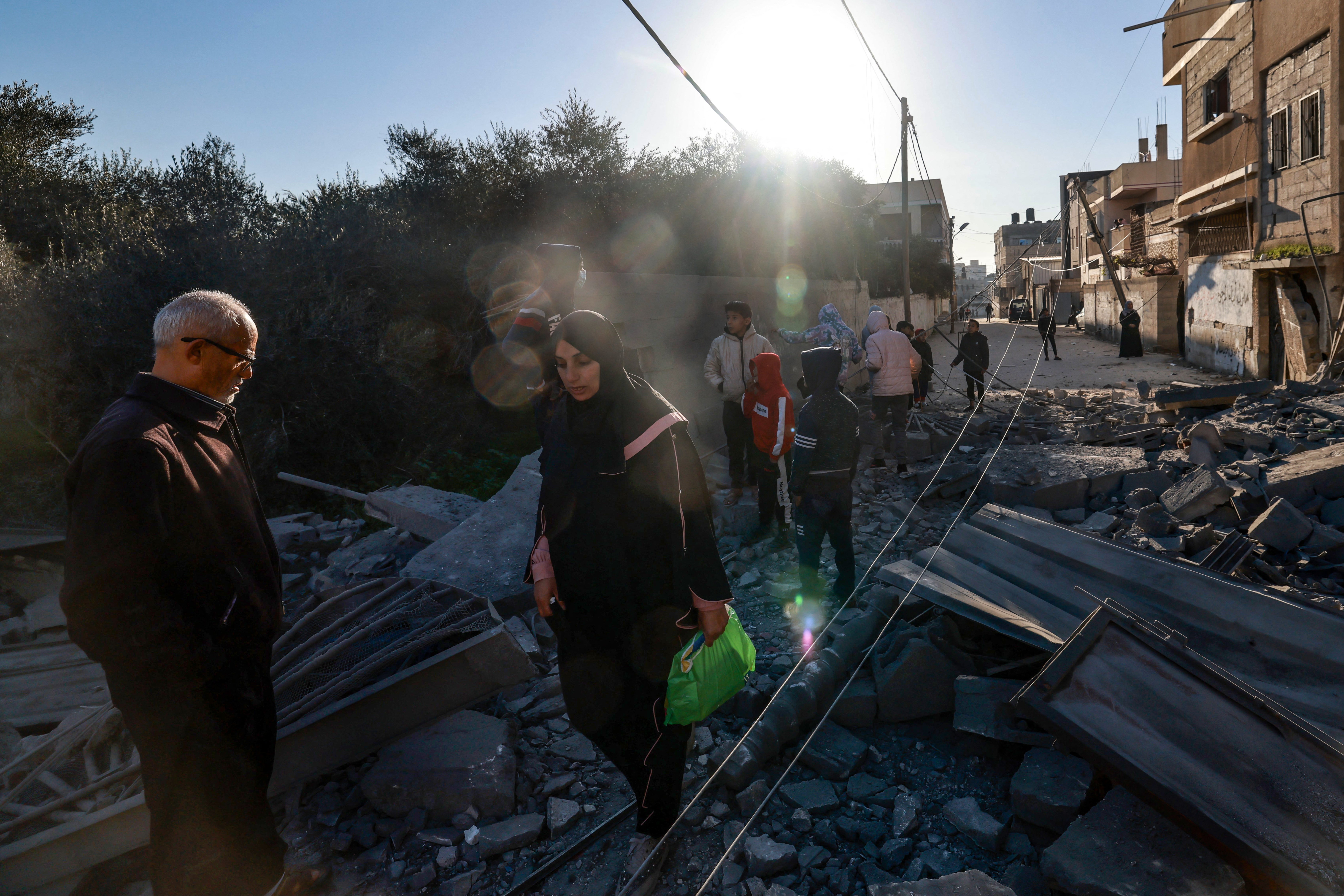 Palestinians walk through the rubble of a building destroyed by Israeli bombardment on Rafah