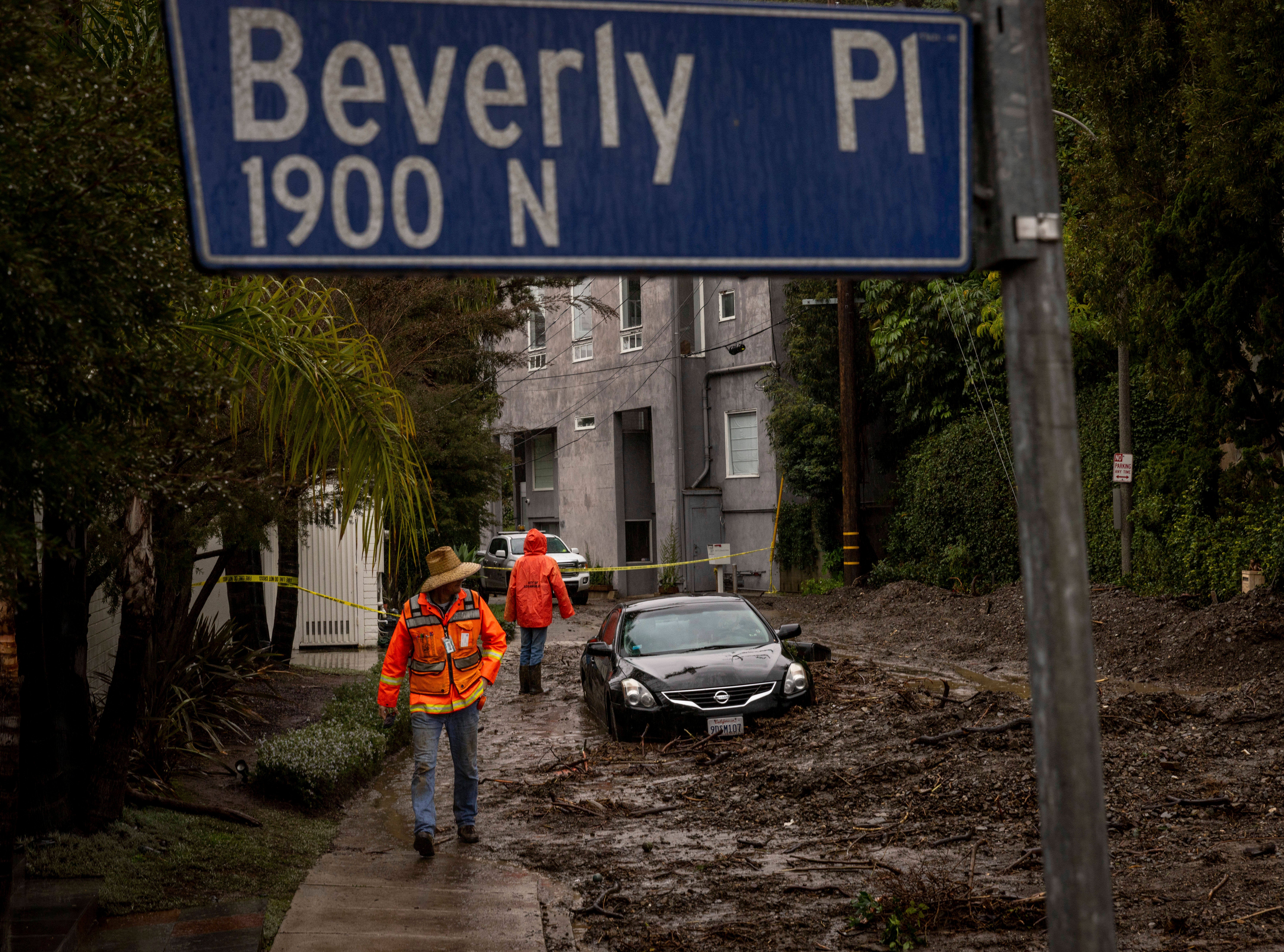 Workers survey a mudslide Tuesday, Feb. 6, 2024, in the Beverly Crest area of Los Angeles