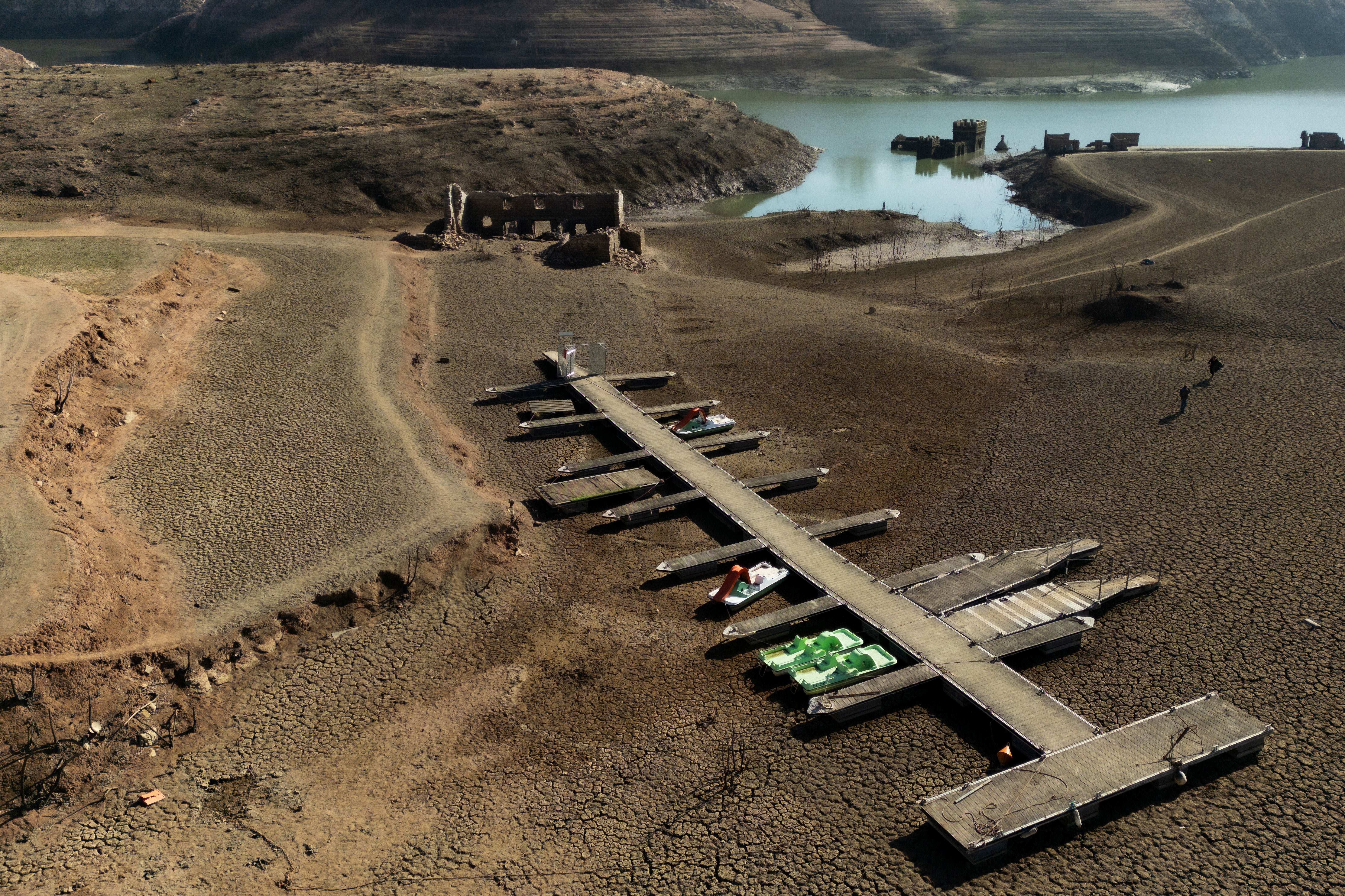 A pier and boats on the dry banks of the depleted Sau reservoir in Girona, Catalonia