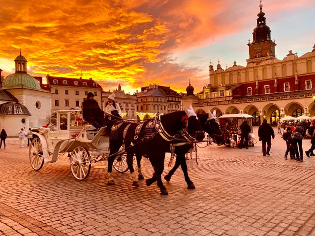 <p>Golden hour: Winter visitors in the main square in Krakow, southern Poland</p>