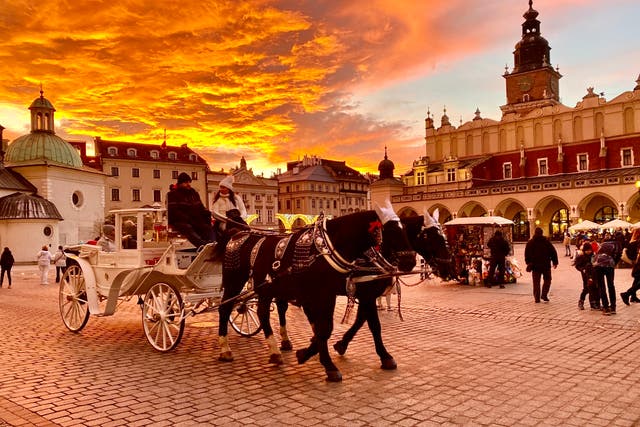 <p>Golden hour: Winter visitors in the main square in Krakow, southern Poland</p>