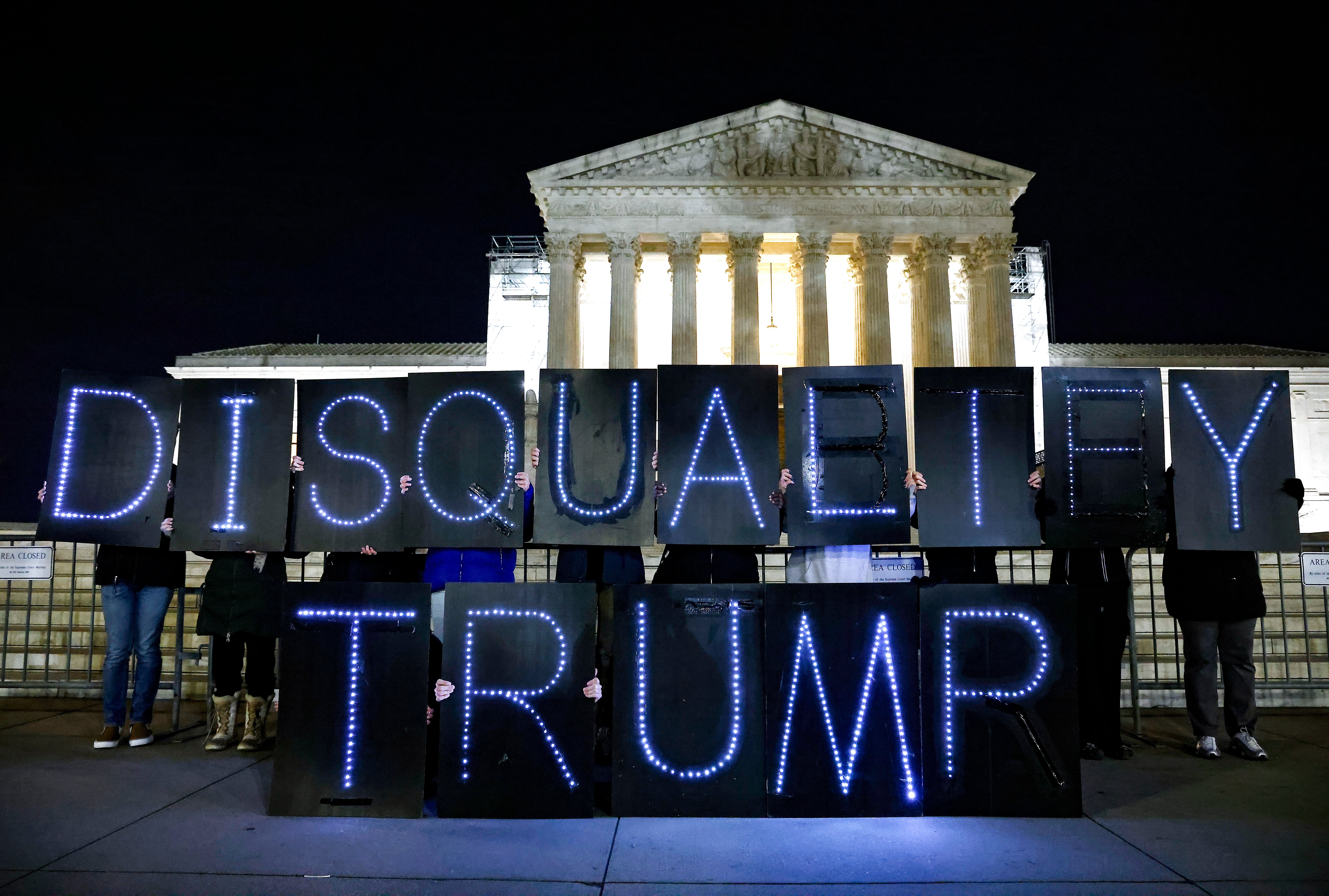 Protesters hold a “disqualify Trump” sign outside the US Supreme Court days before a hearing to consider his challenge to a Colorado Supreme Court ruling that would remove him from the state’s ballots.