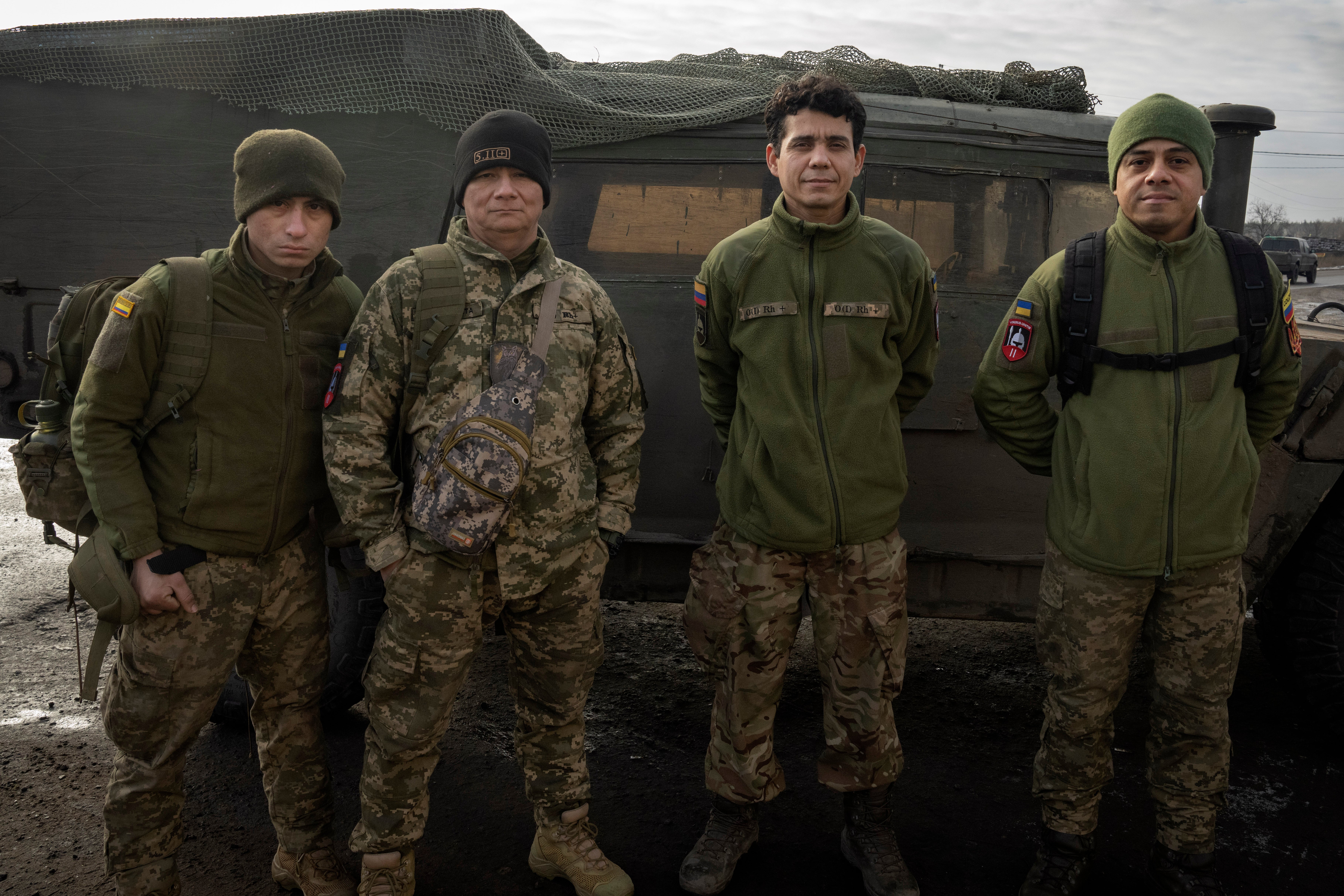 Colombian veterans who joined the Ukrainian armed forces to help fight Russia pose for a photo near their Humvee