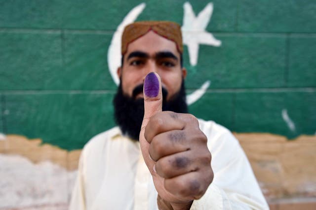 <p>A voter shows his thumb after casting a ballot at a polling station during general elections in Karachi</p>