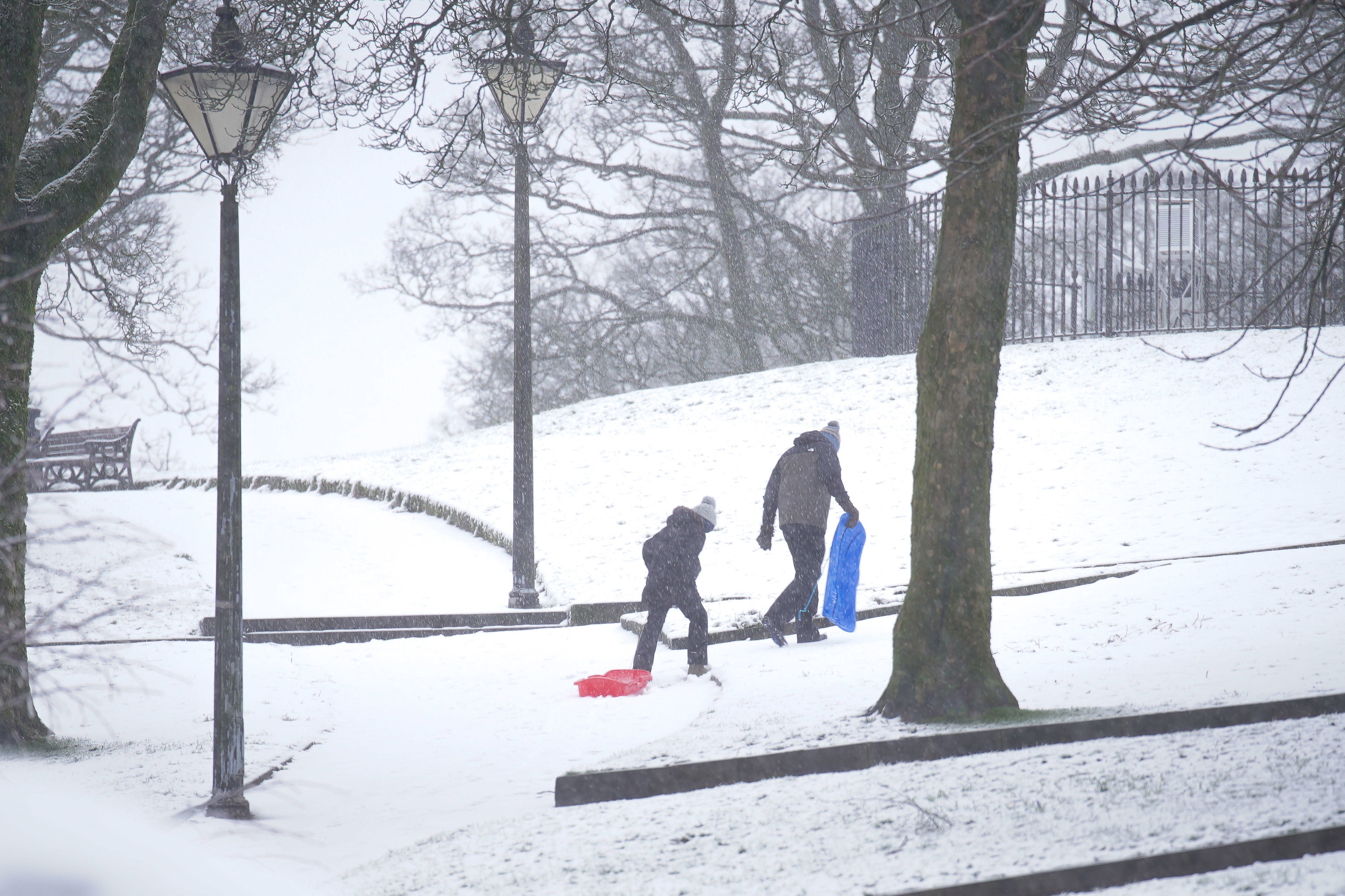 People carry sleds up a hill in the Pavilion Gardens