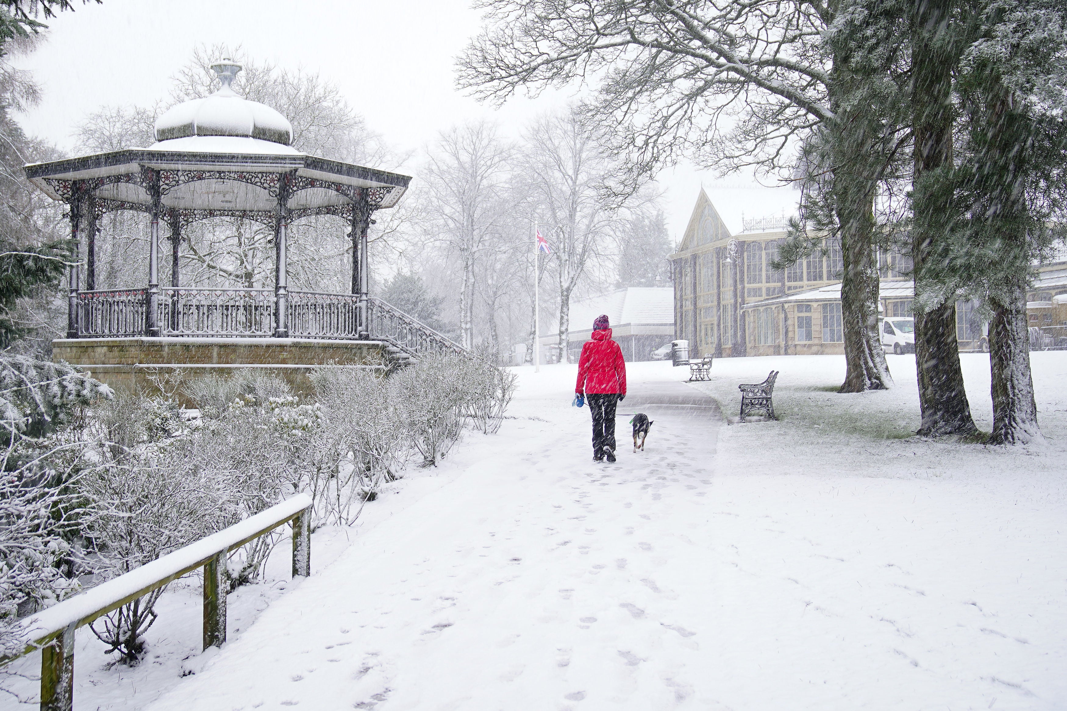 A person walks a dog through Pavilion Gardens in the Peak District