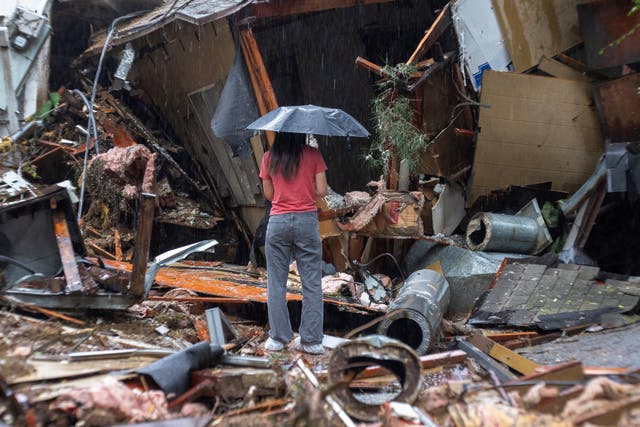 <p>A woman stands among the wreckage of a house that was abruptly destroyed by a landslide as a historic atmospheric river storm inundates the Hollywood Hills area of Los Angeles, California, on February 6,</p>