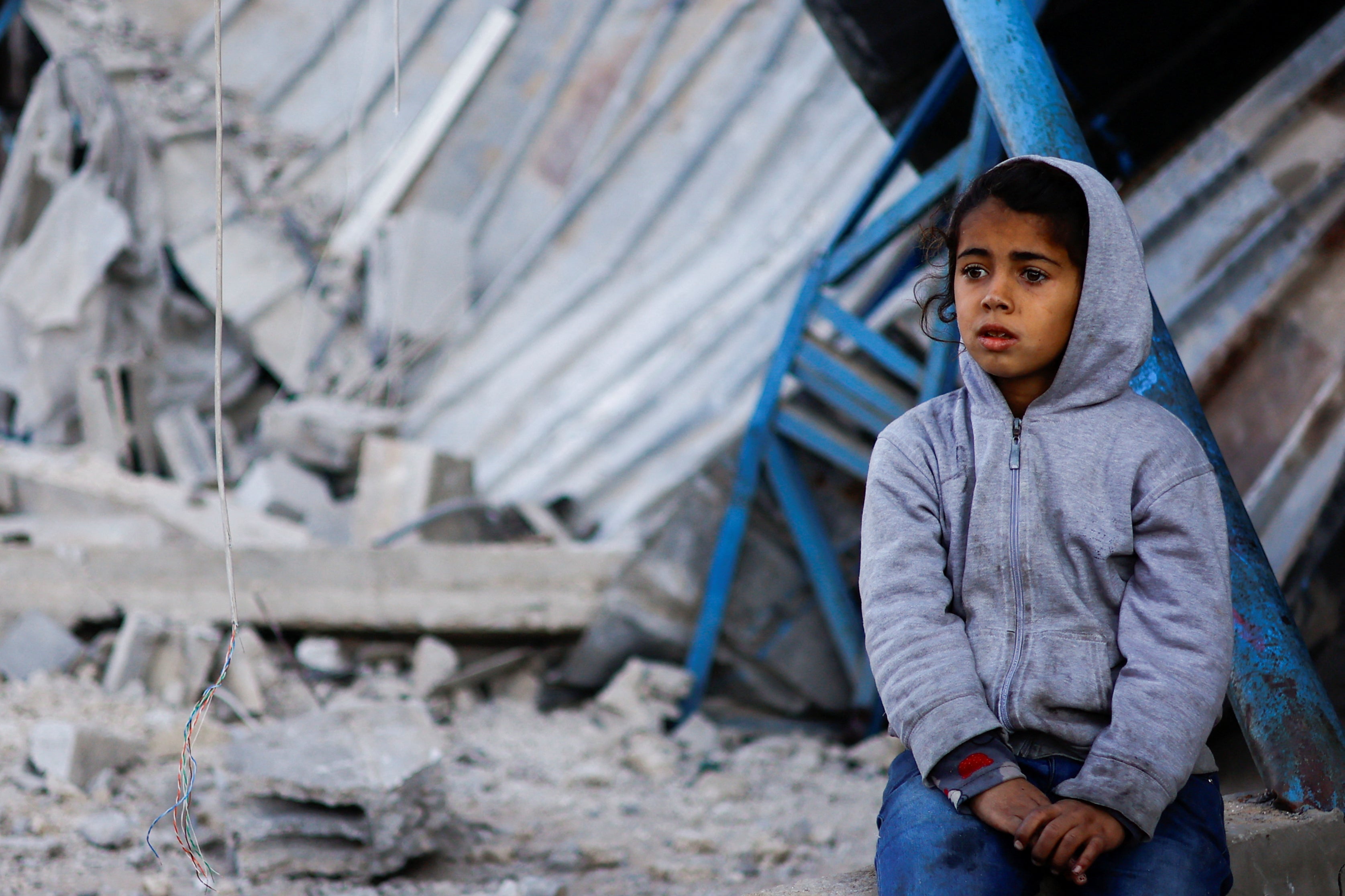 Palestinian child sits at the site of an Israeli strike on a house in Gaza’s Rafah