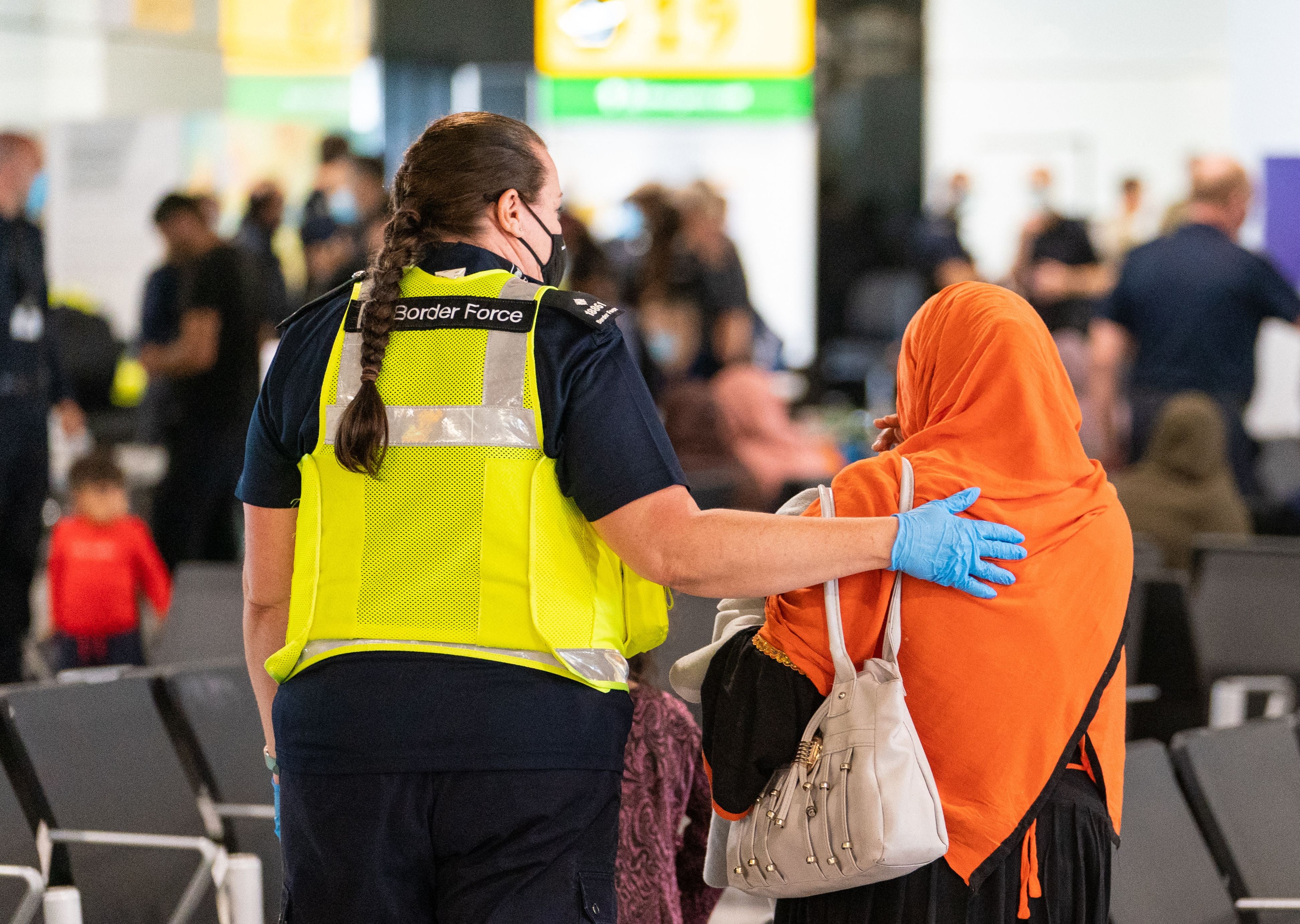 A member of Border Force staff assists an Afghan refugee on her arrival on an evacuation flight from Afghanistan, at Heathrow