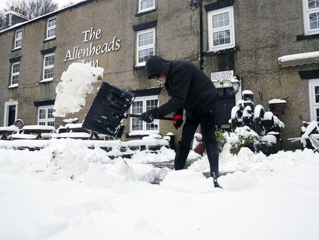 <p>A person clears snow outside The Allenheads Inn in Allenheads, Northumberland</p>