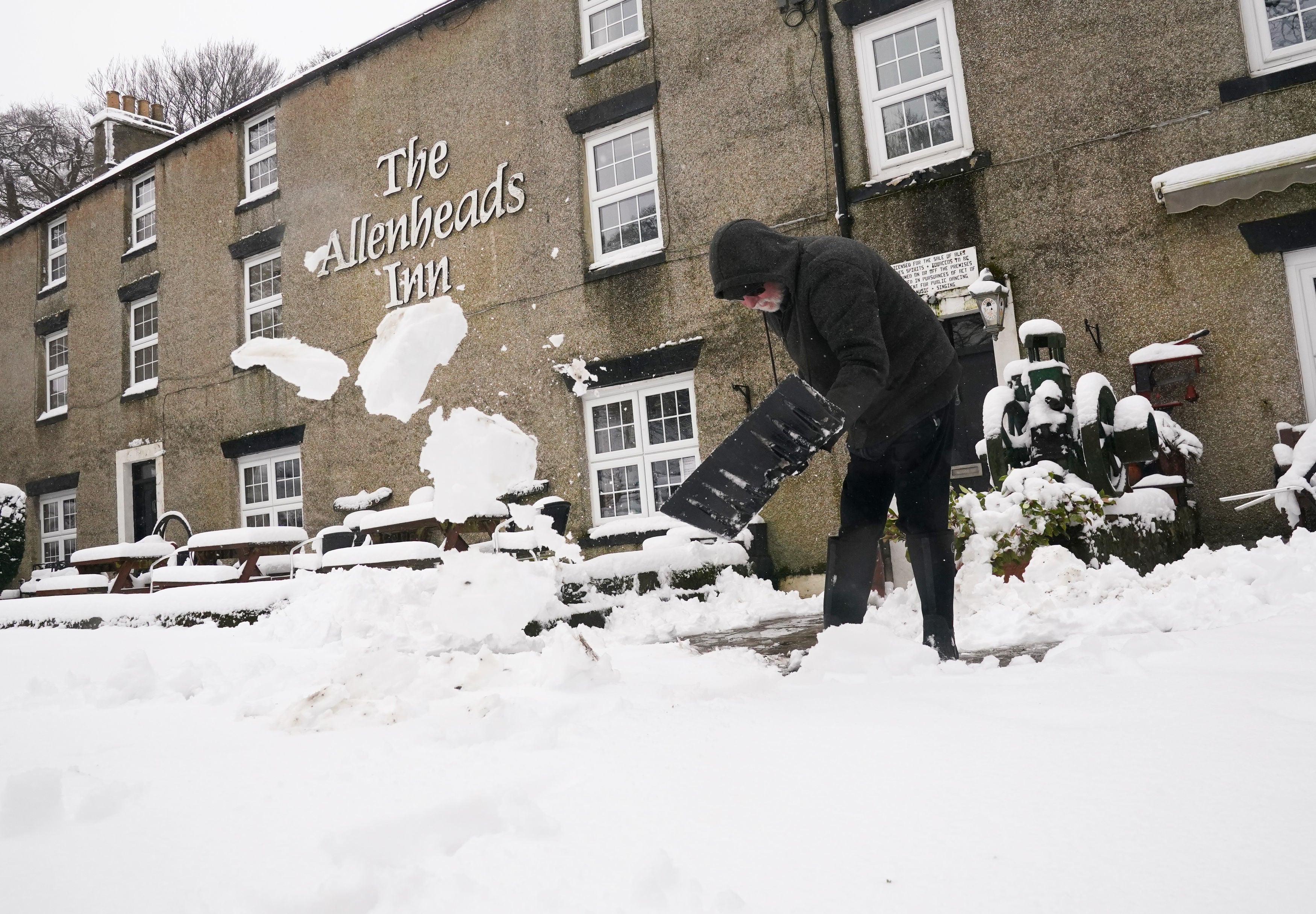 A person clears snow outside The Allenheads Inn in Allenheads, Northumberland