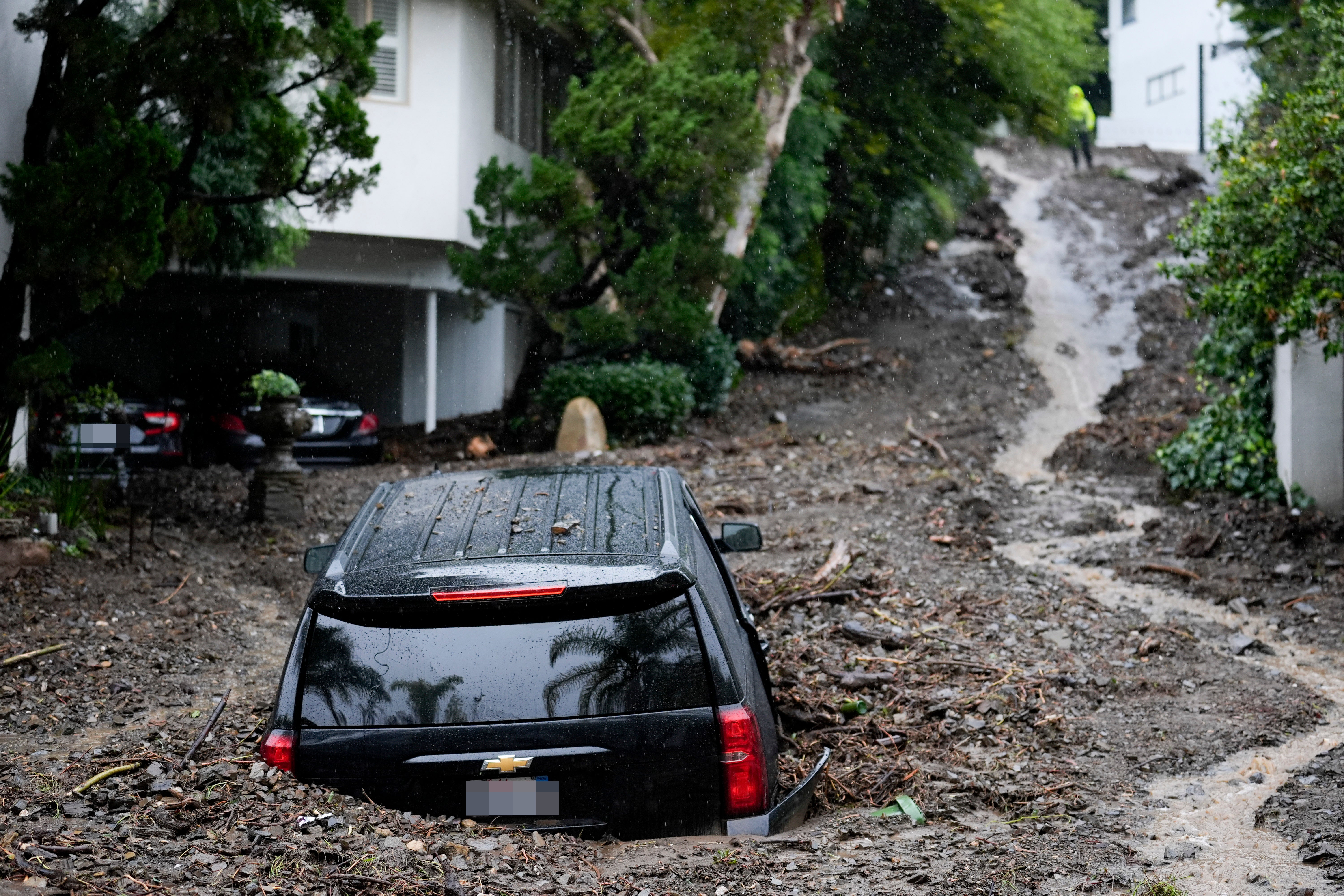 An SUV sits buried by a mudslide, Monday, Feb. 5, 2024, in the Beverly Crest area of Los Angeles