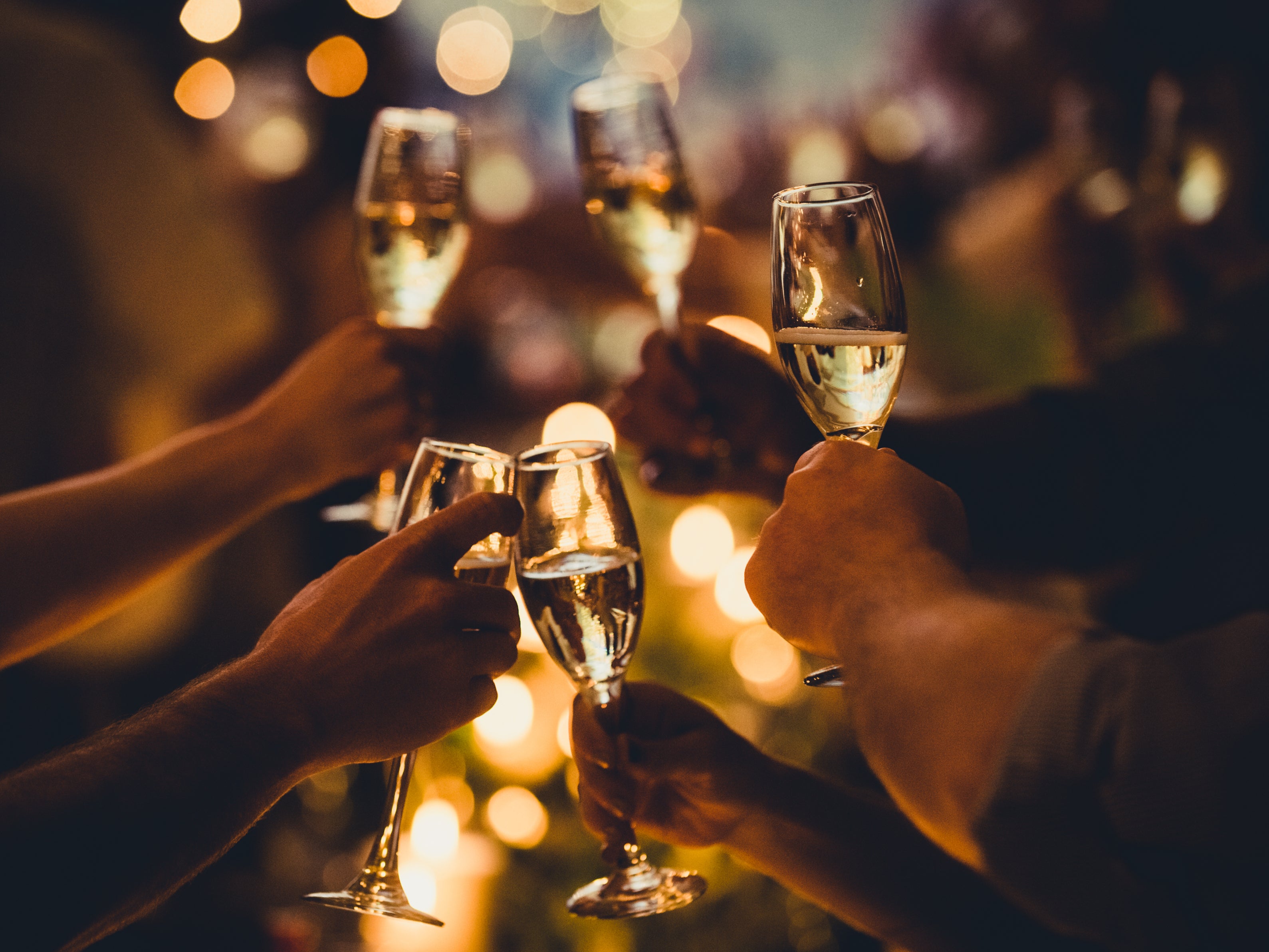 <p>Numerous hands holding champagne flutes with champagne celebratory toast silhouettes</p>