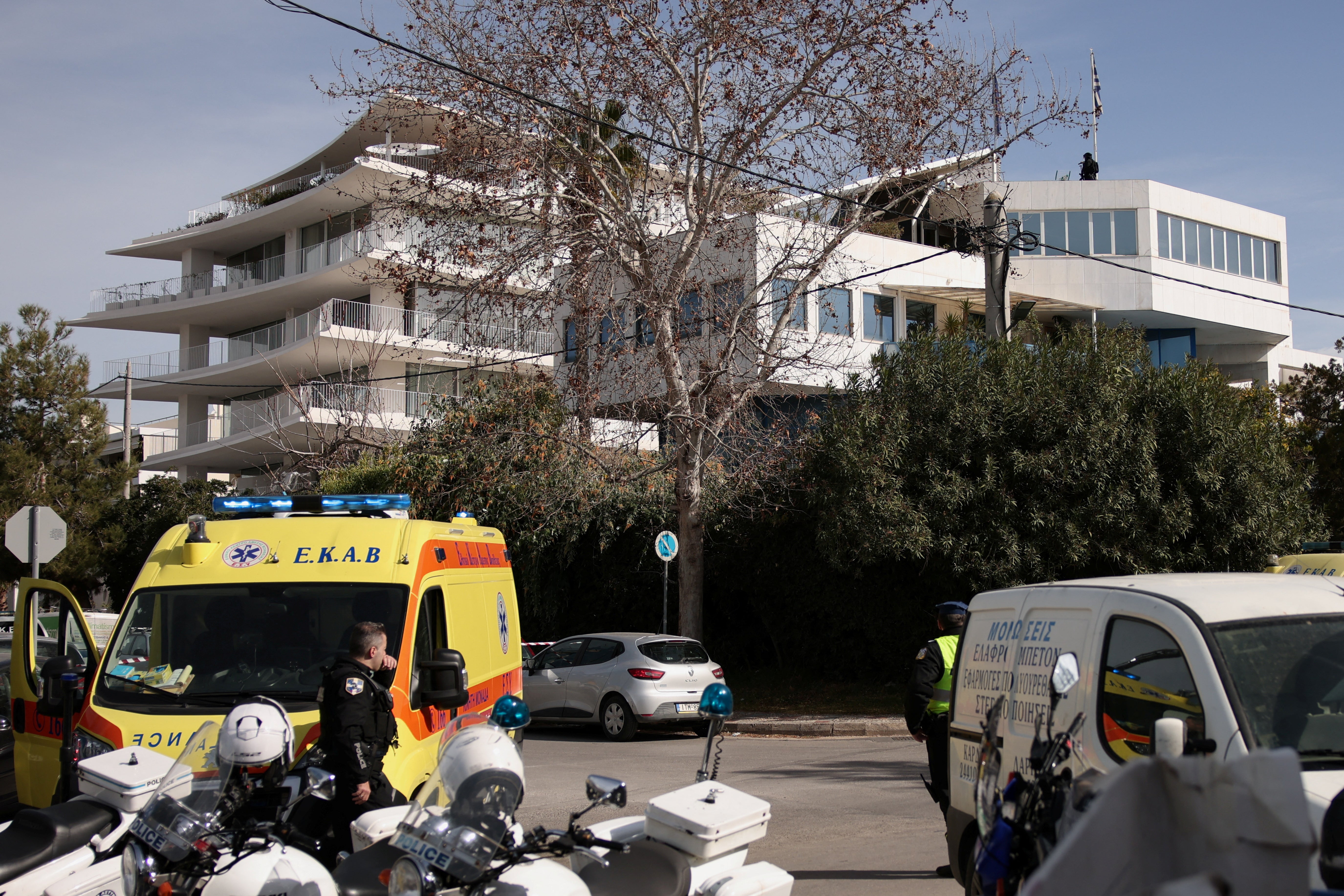A police officer stands on the building terrace while police secure the area around the building of a shipping company following a shooting in Athens